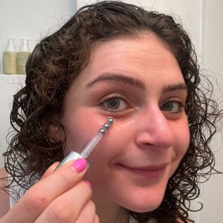 Woman rolls the eye serum directly on her under-eyes.