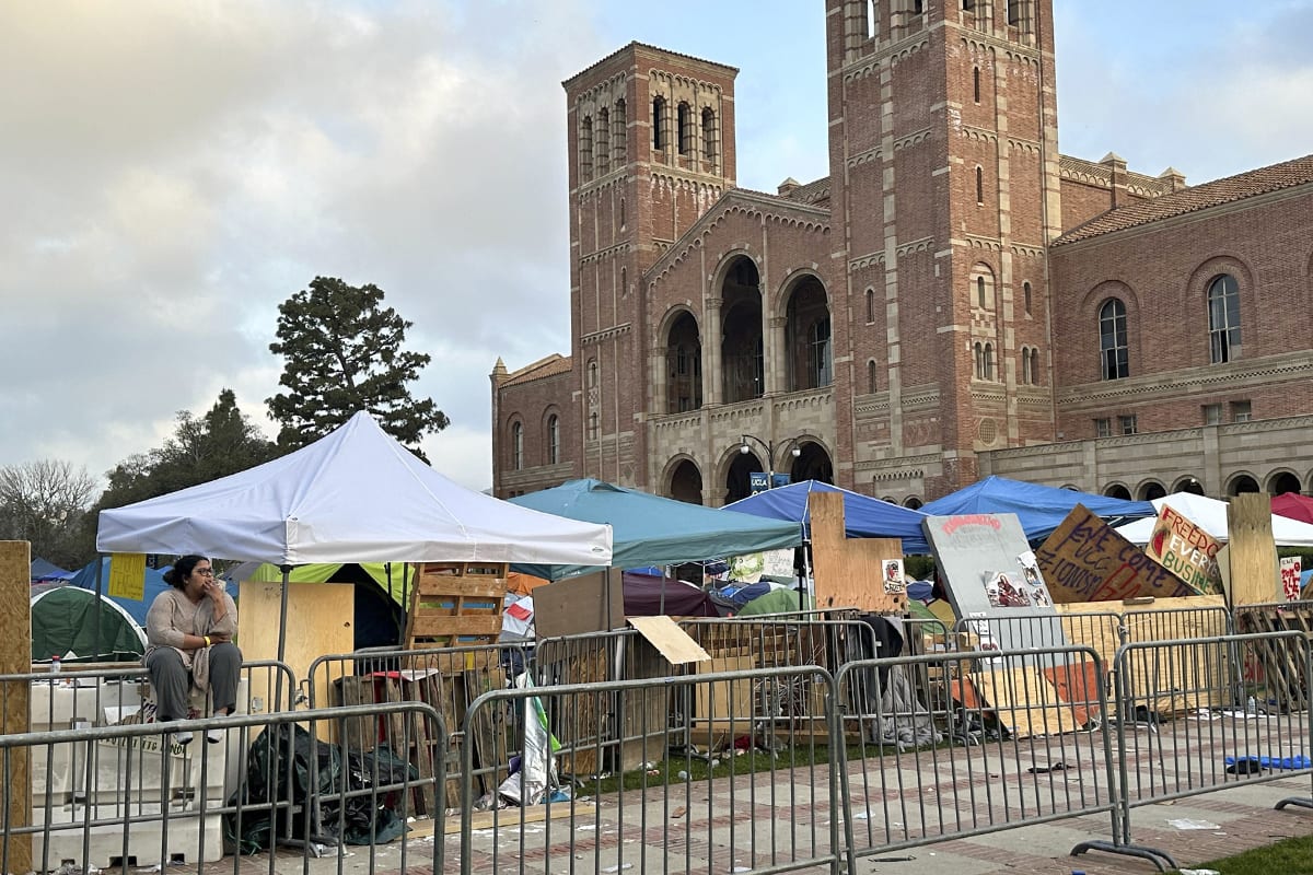 A demonstrator sits in front of barricades set up to protect an encampment on the UCLA campus on Wednesday, May 1, 2024, in Los Angeles. 