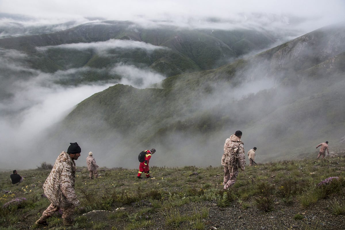 Rescue team members search an area near the crash site of a helicopter carrying Iranian President Ebrahim Raisi 