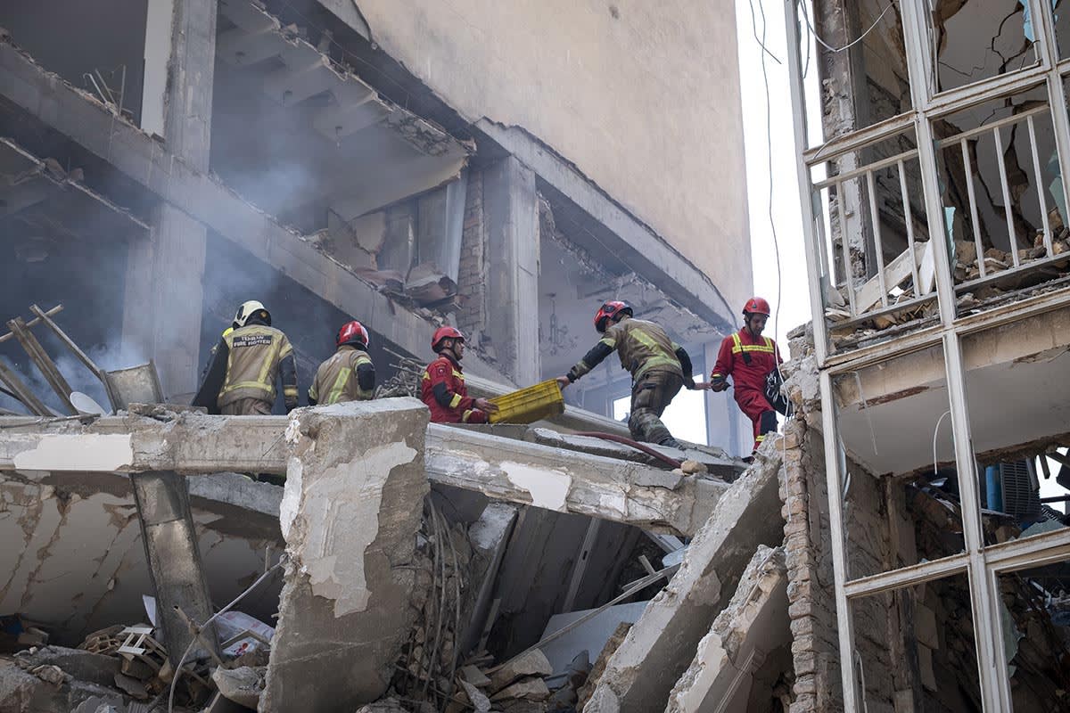 Firefighters work at the scene of an apartment building destroyed by Israeli strikes in Tehran, Iran, on June 13, 2025.