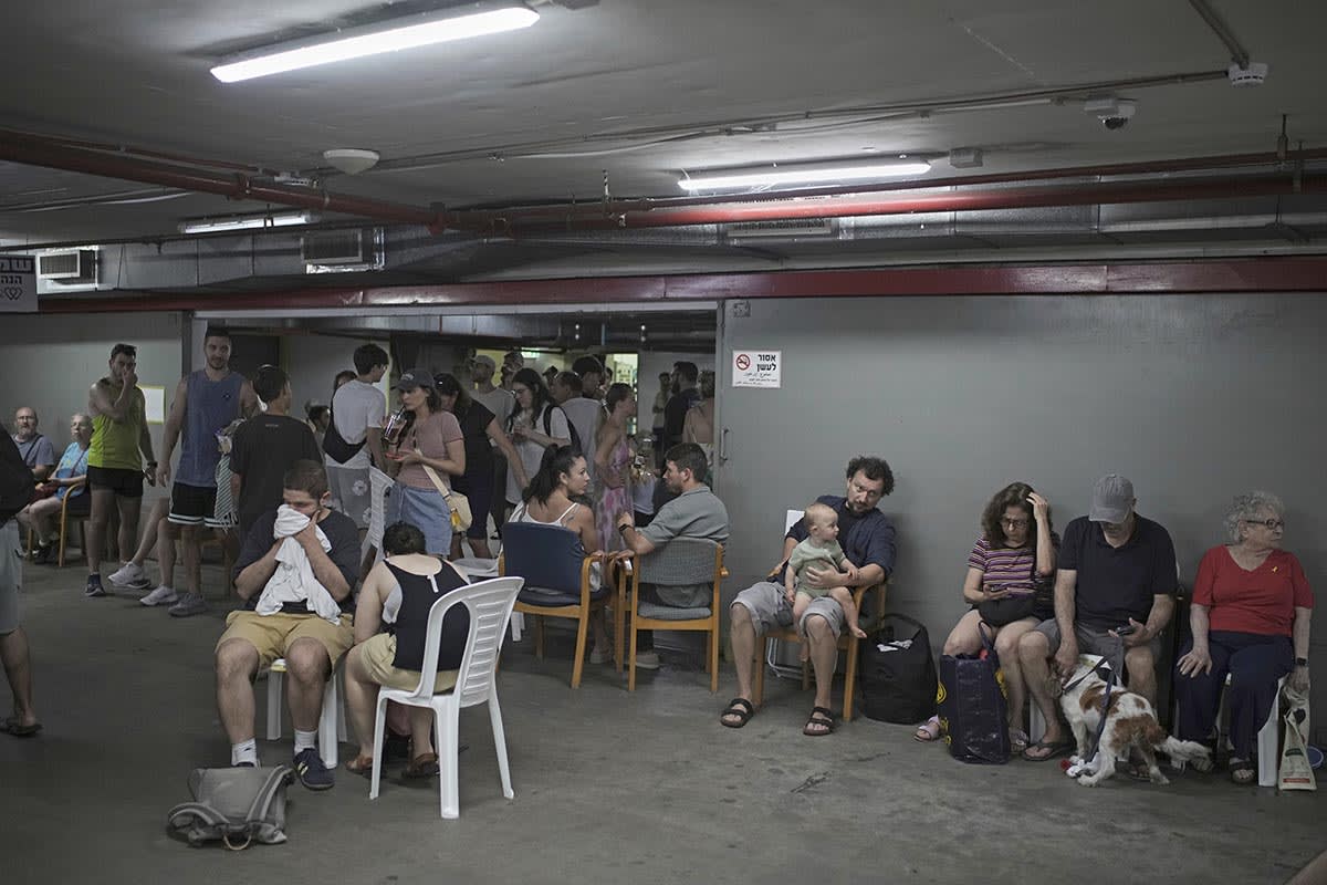 People take shelter as air raid sirens warn of incoming Iranian strikes in Tel Aviv, Israel, Friday, June 20, 2025.