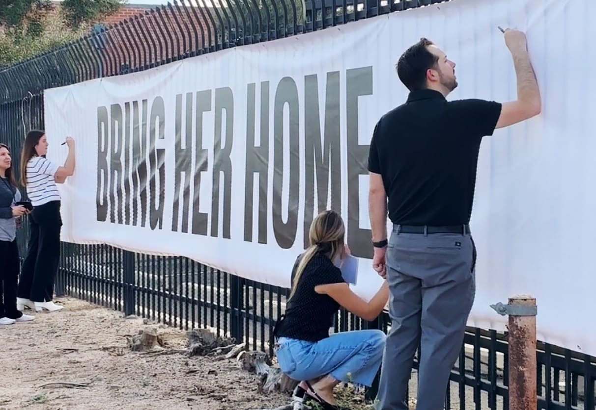 Well-wishers write messages of support for the family of Nancy Guthrie on a banner outside KVOA in Tucson.