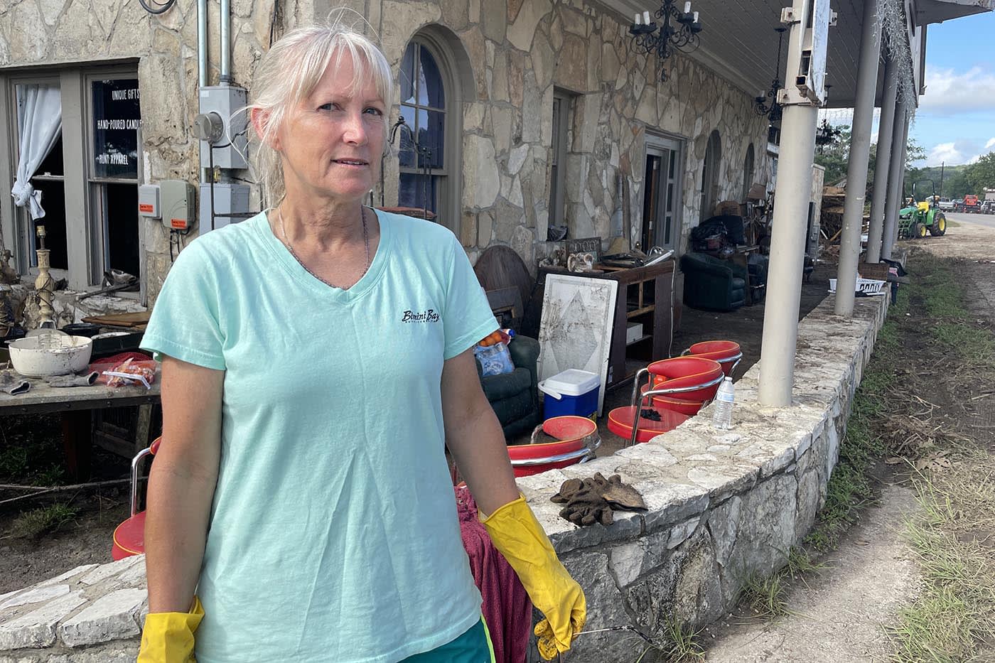 Andi Fell, whose son survived floodwaters that swept through her family’s Hunt, Texas home, wears rubber gloves to continue cleanup and debris removal.