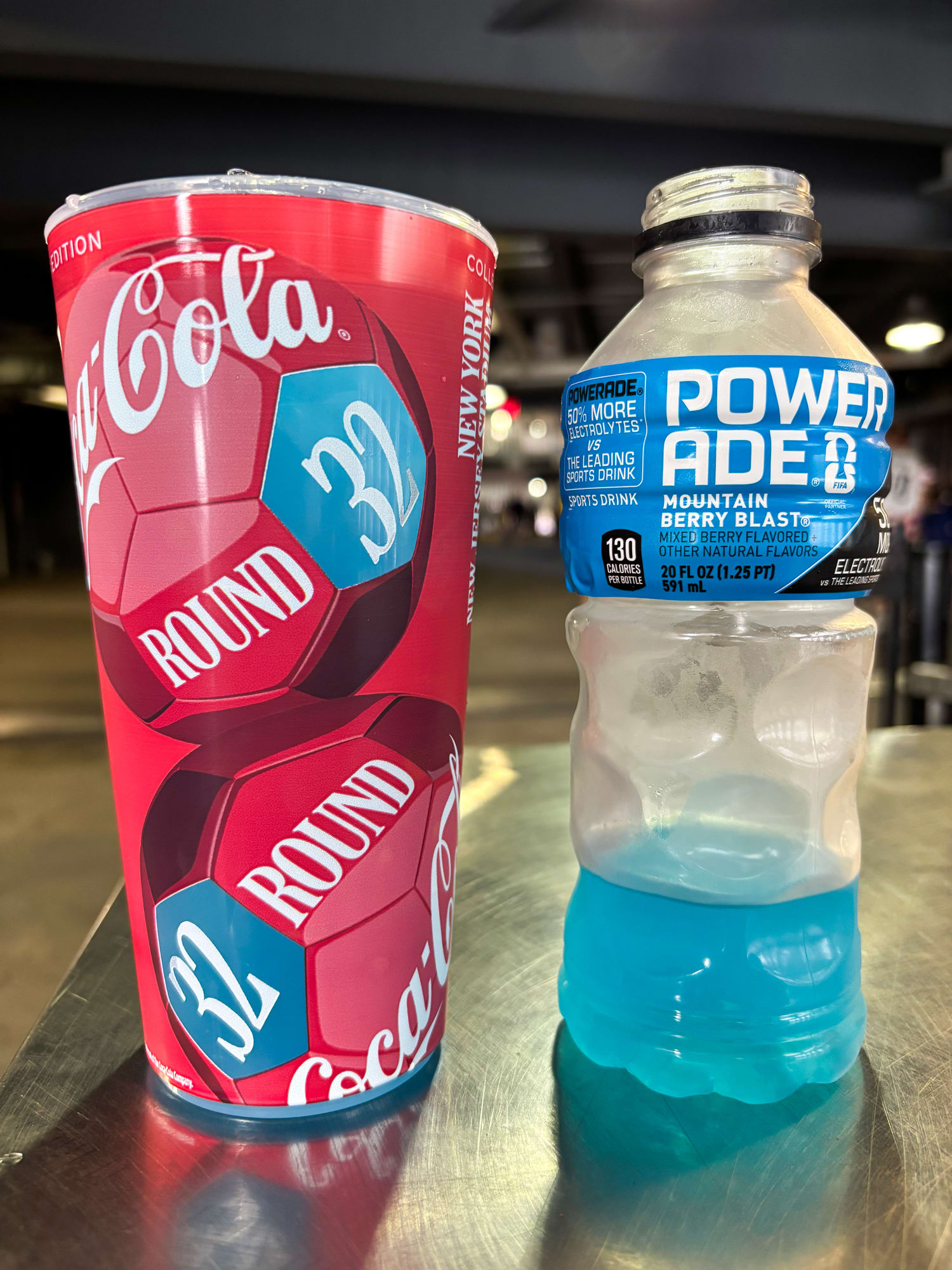 A Coca Cola cup next to a Powerade bottle