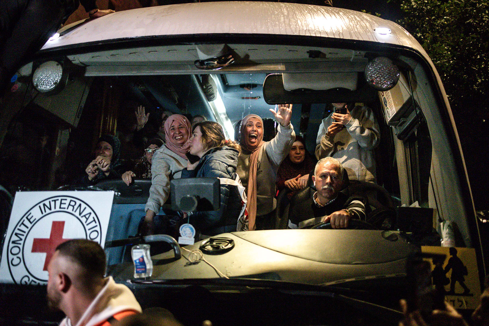 People wave from the inside of a bus