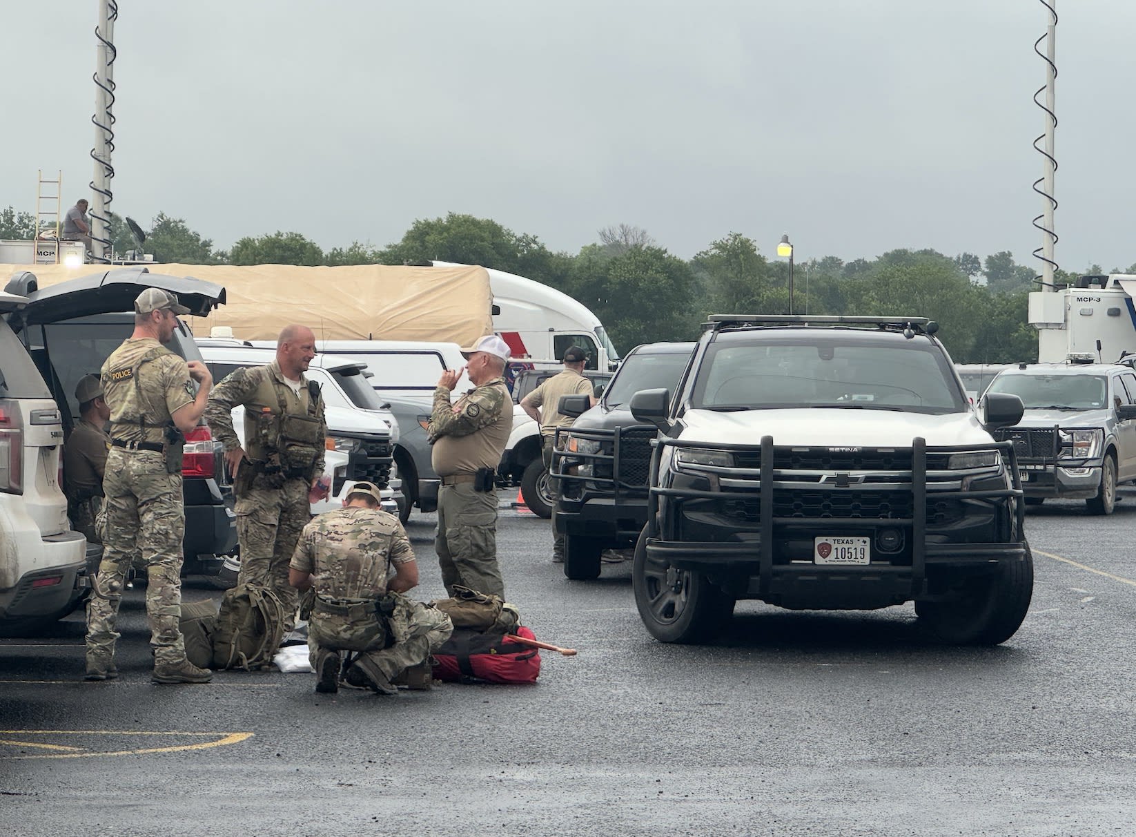 Police officers stand around in a parking lot