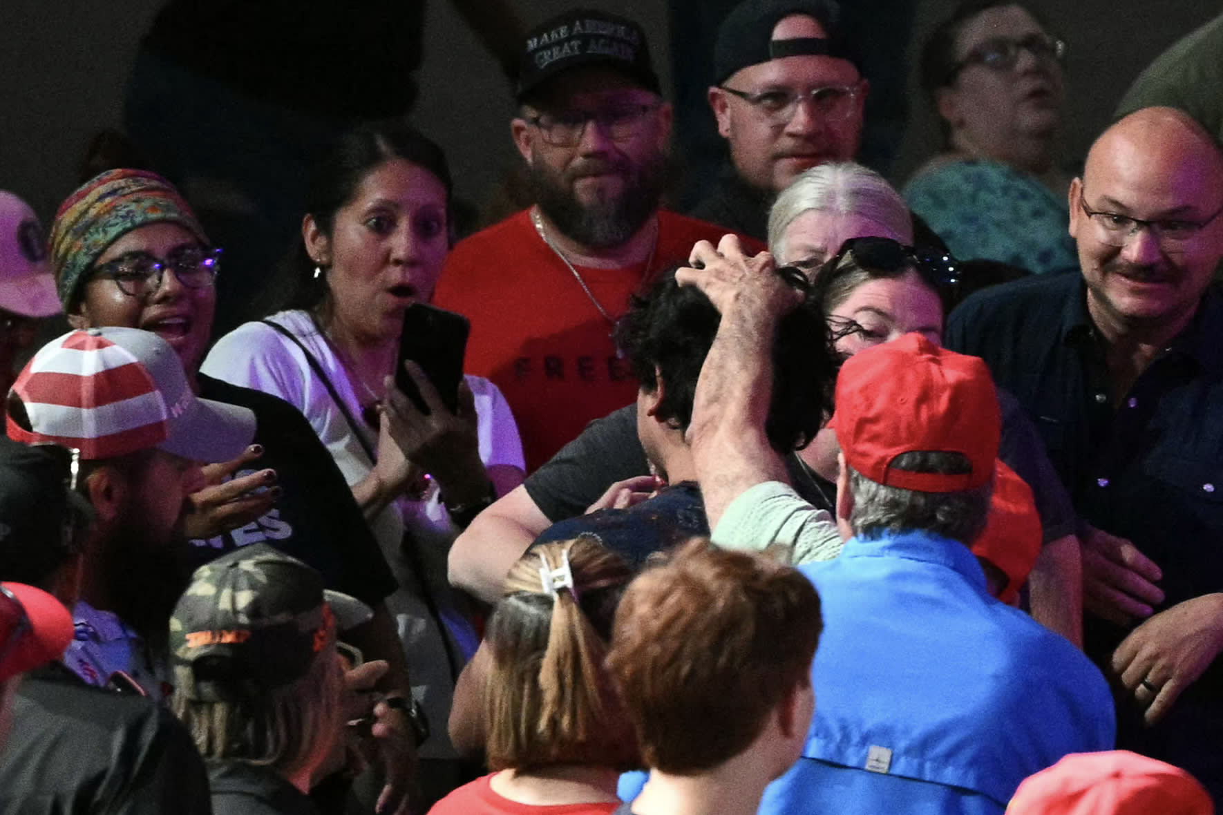 A crowd of people surround a protestor during a Trump rally.