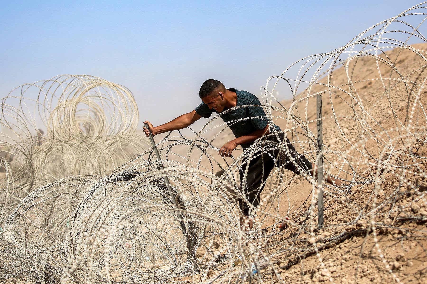 A man attempts to remove parts of the barbed-wire fence at the so-called "Netzarim corridor" near Nuseirat in the central Gaza Strip on Oct. 10, 2025, as people make their way back to Gaza City.