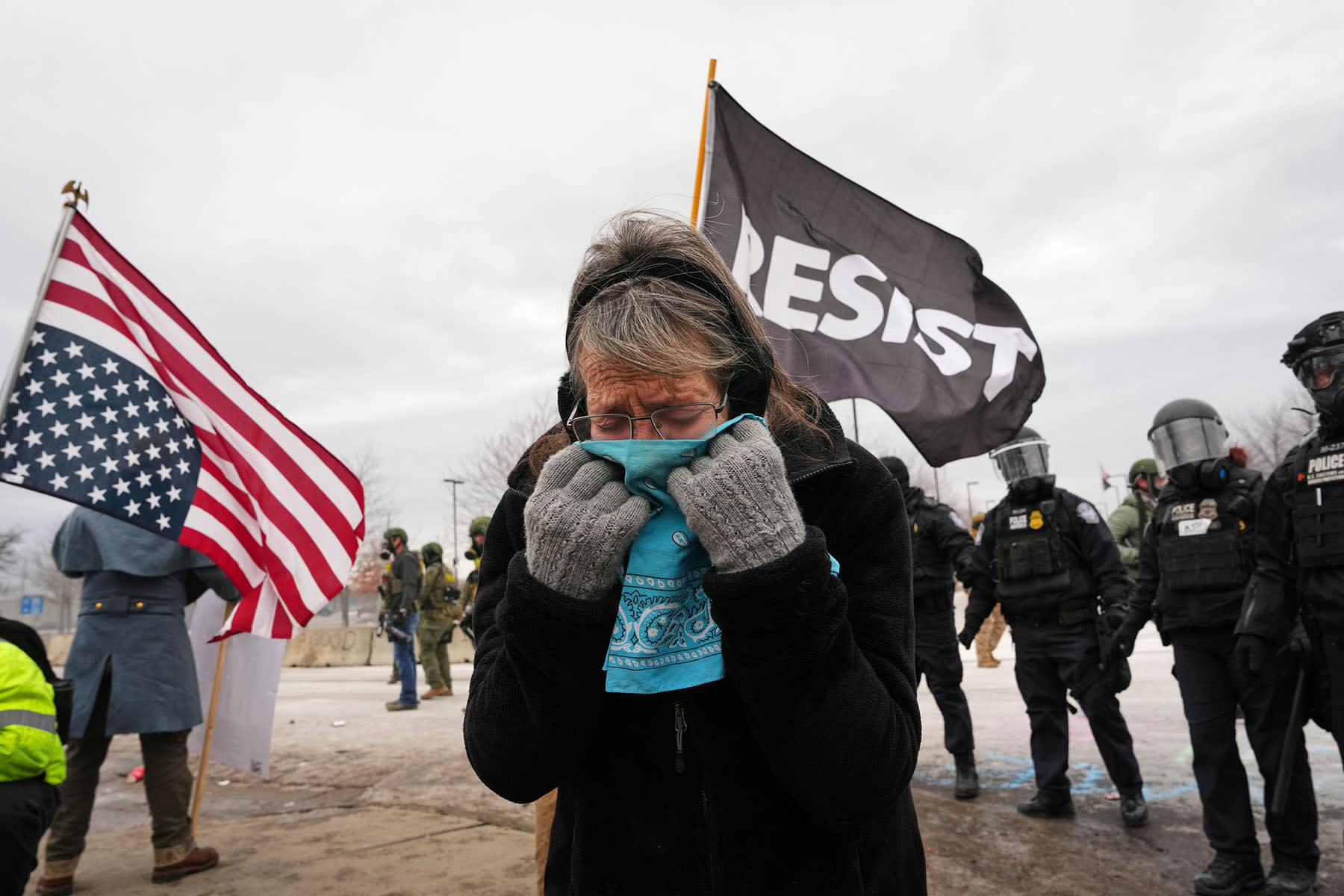 A woman covers her face to protect from tear gas as federal immigration officers confront protesters outside Bishop Henry Whipple Federal Building, Thursday, Jan. 15, 2026, in Minneapolis. 