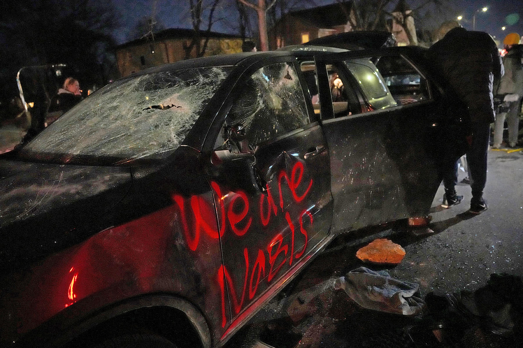 People look vandalized car believed to belong to federal law enforcement in north Minneapolis on Jan, 14, 2026.