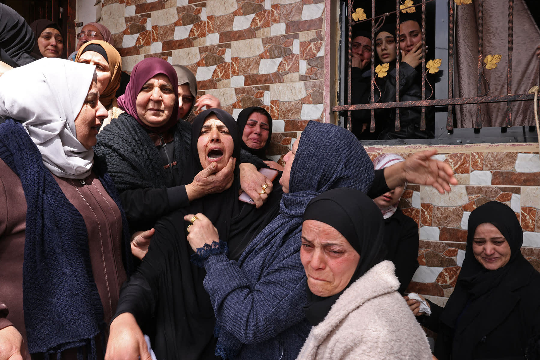 Family members mourn one of the three Palestinian women killed in Iranian missile attacks in Beit Awa in the West Bank on March 19, 2026. 