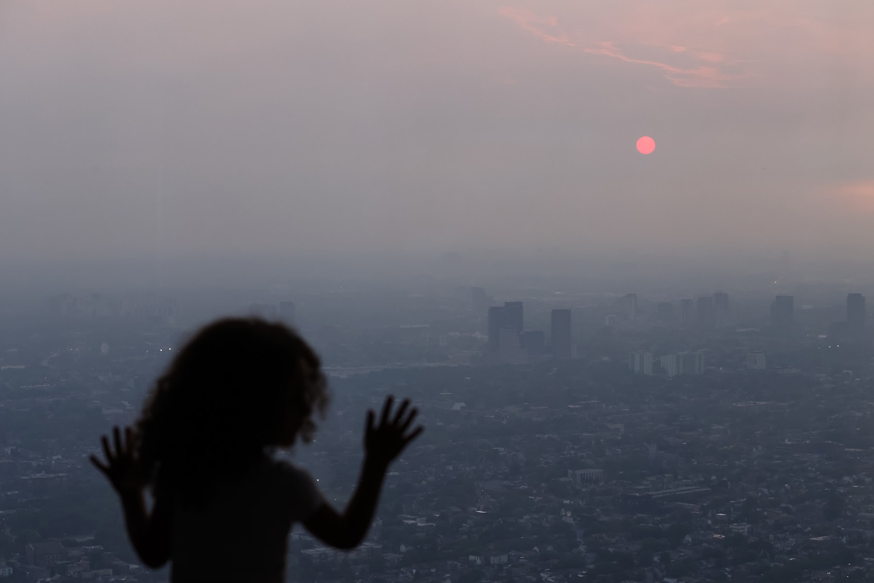 A child looks out from the observation deck of the CN Tower in Toronto as smoke from wildfires in Northwestern Ontario blankets the city