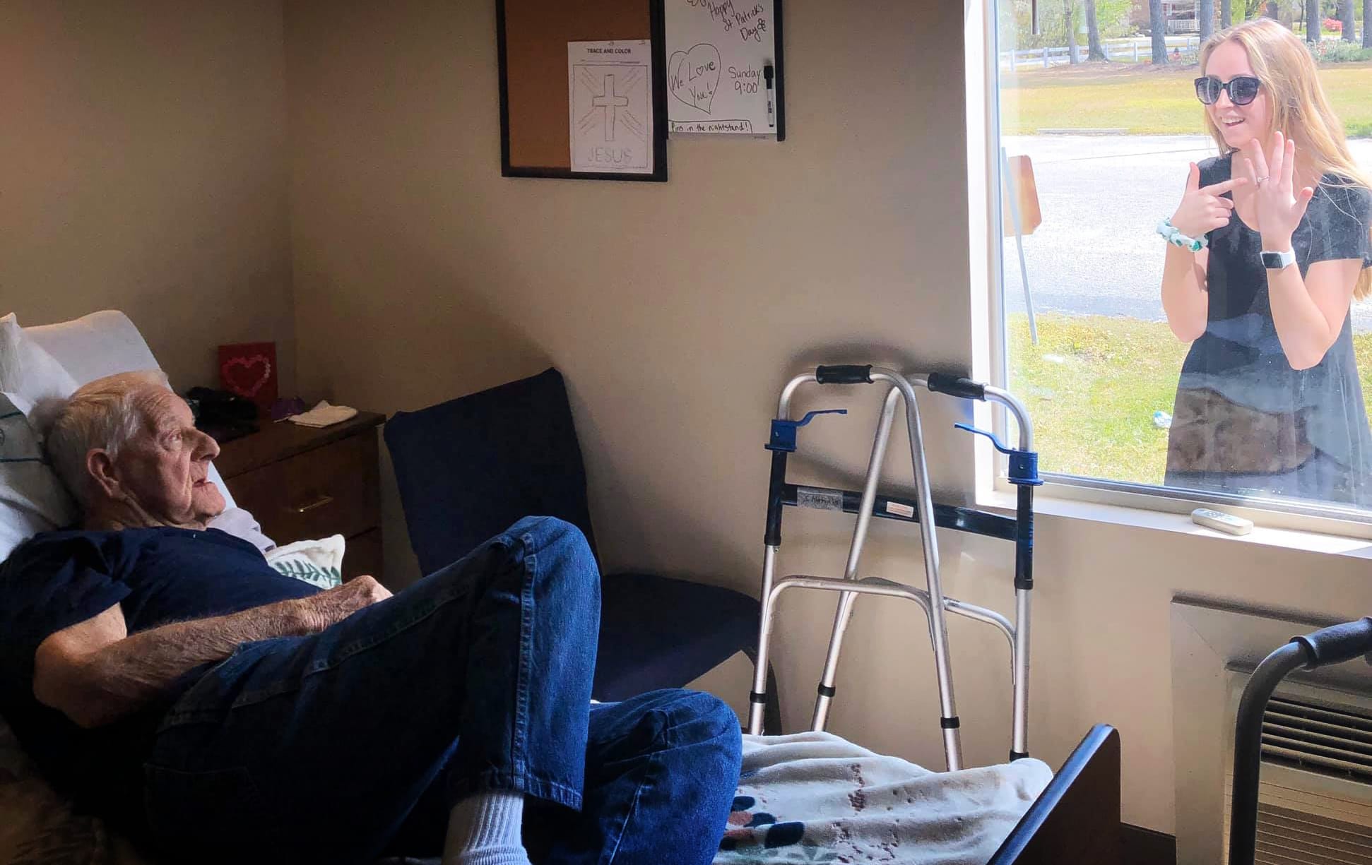 Image: Carly Boyd and her grandfather, Shelton, speak through a window at the locked down Premier Living and Rehab Center in North Carolina.