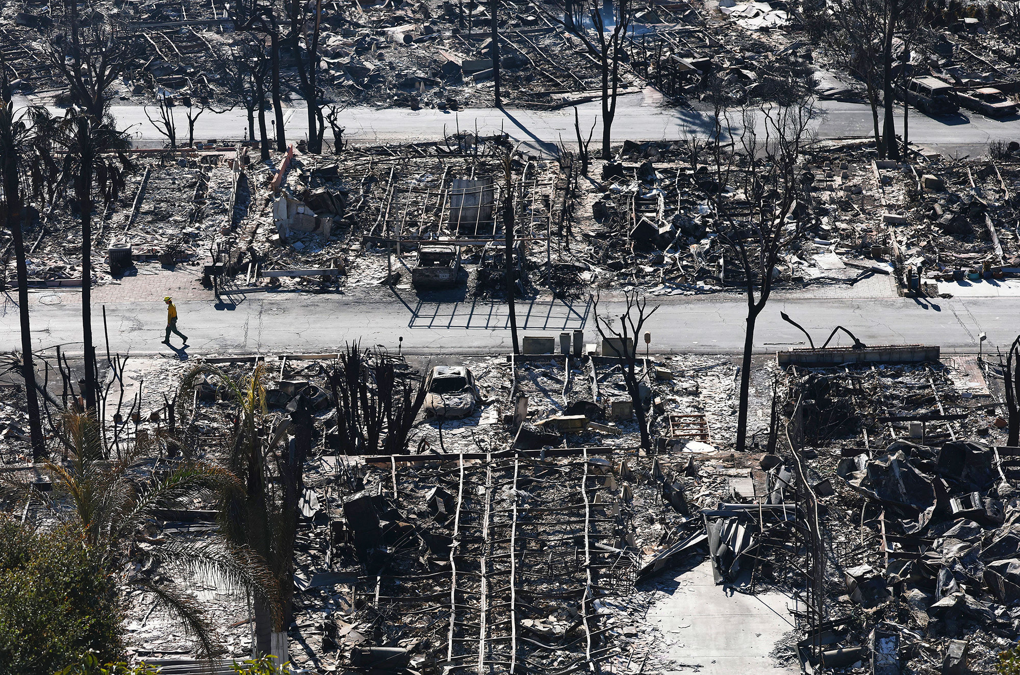 A firefighter walks past homes destroyed in the Palisades Fire on Jan. 13, 2025 in Pacific Palisades, Calif.