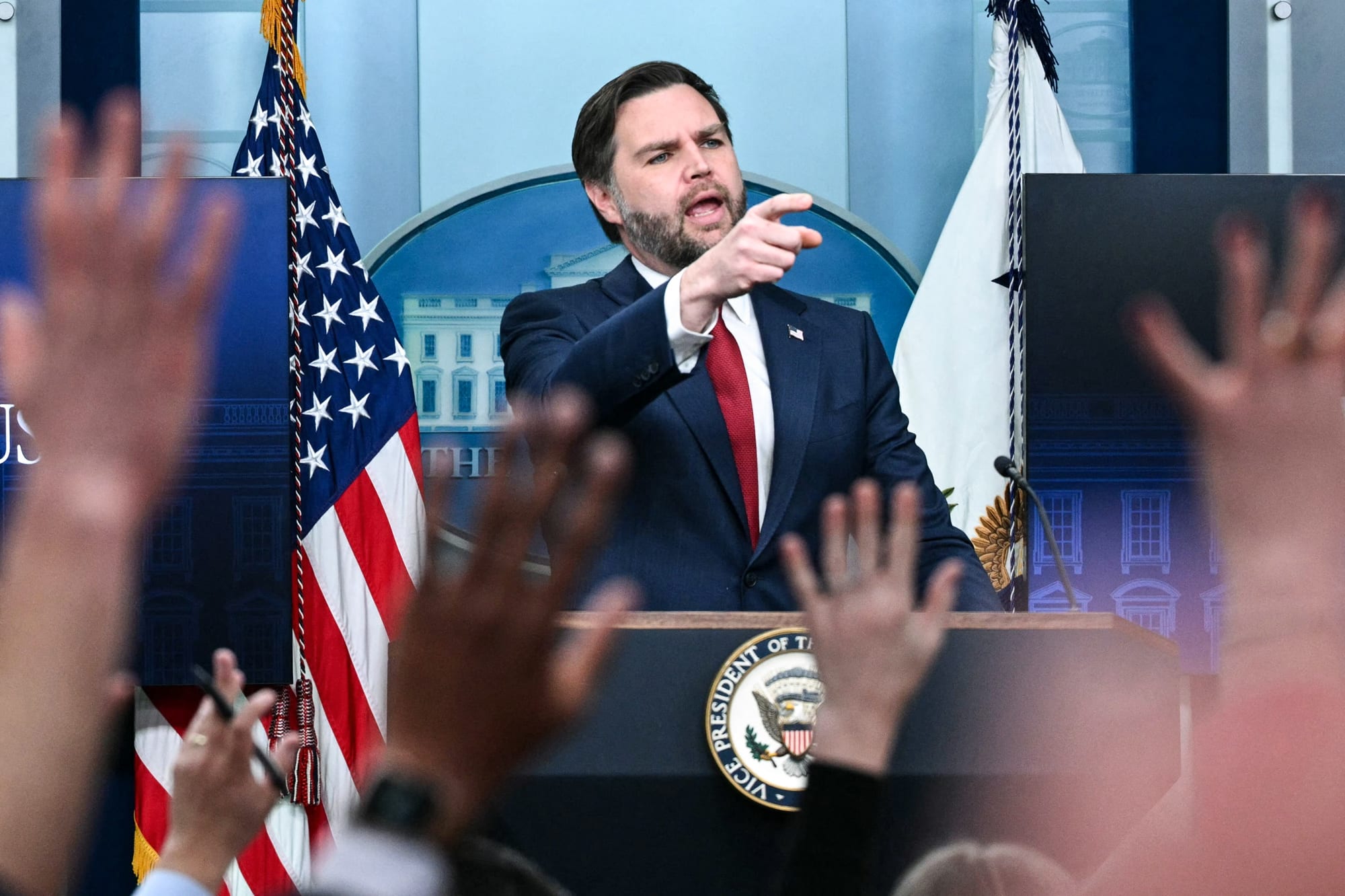 JD Vance speaks at a podium as people raise their hands in the audience