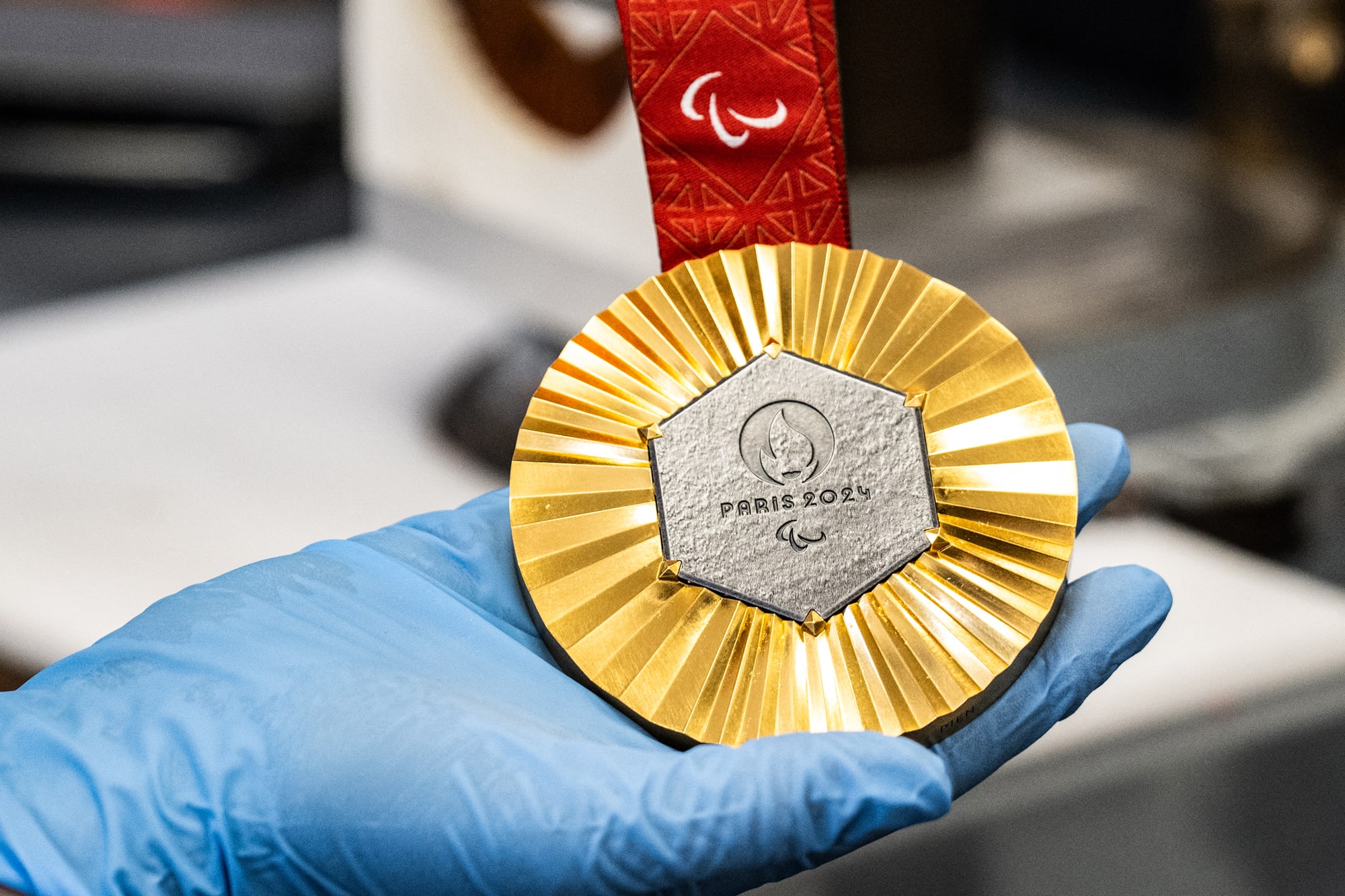 A gloved hand holds an Olympic gold medal