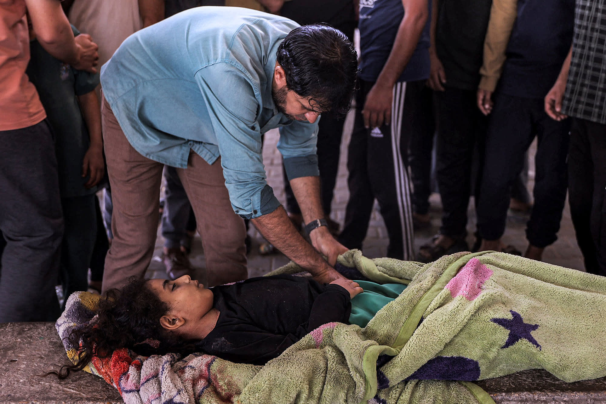 A man wraps a girl in a blanket who was killed in the bombardment of a school serving as a displacement shelter in the Jabalia refugee camp in the northern Gaza Strip on Oct. 9, 2024.