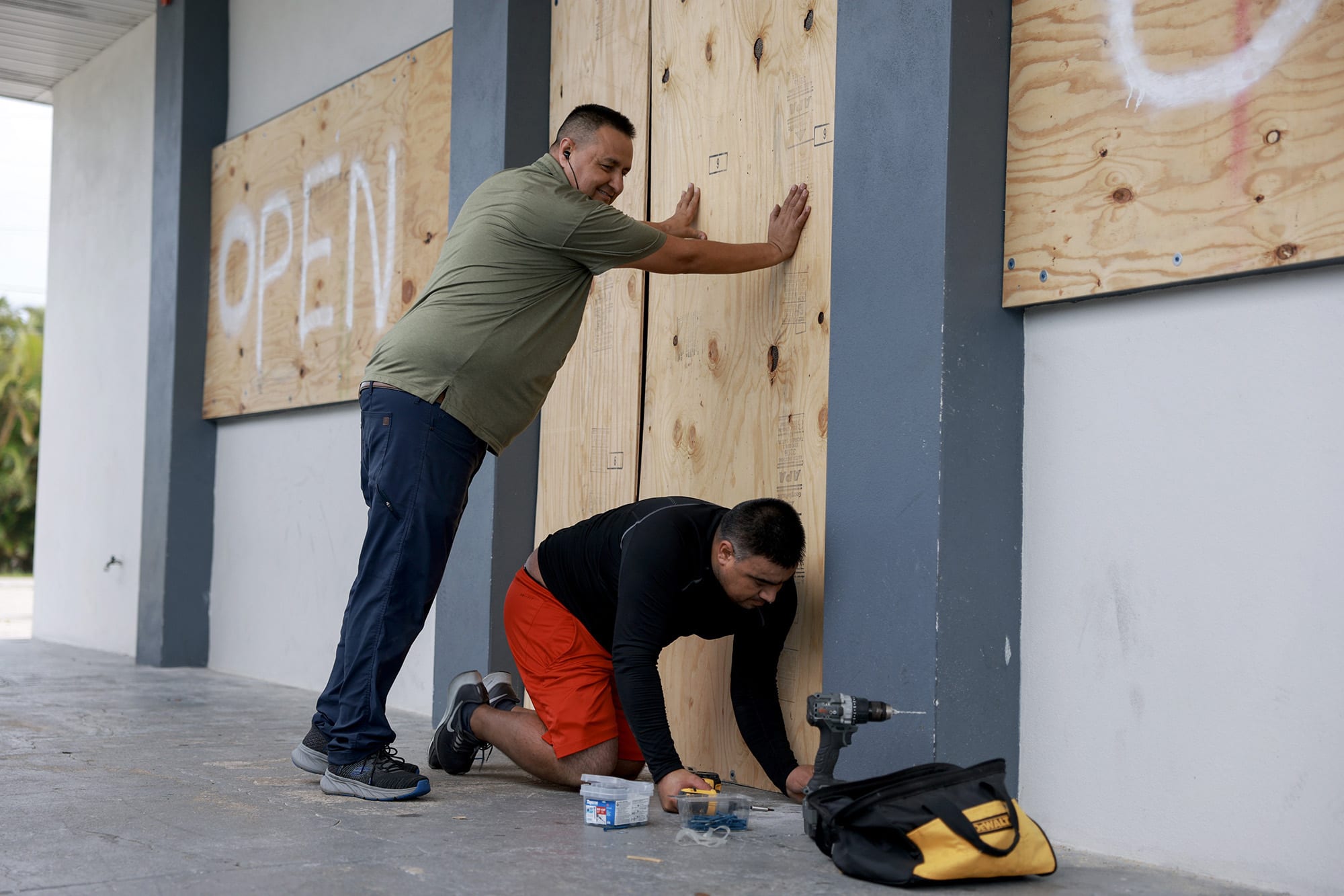Salvador Gonzalez, left, and Jorge Leon place plywood over the windows of a business before Hurricane Milton's arrival on October 9, 2024 in Fort Myers, Fla.