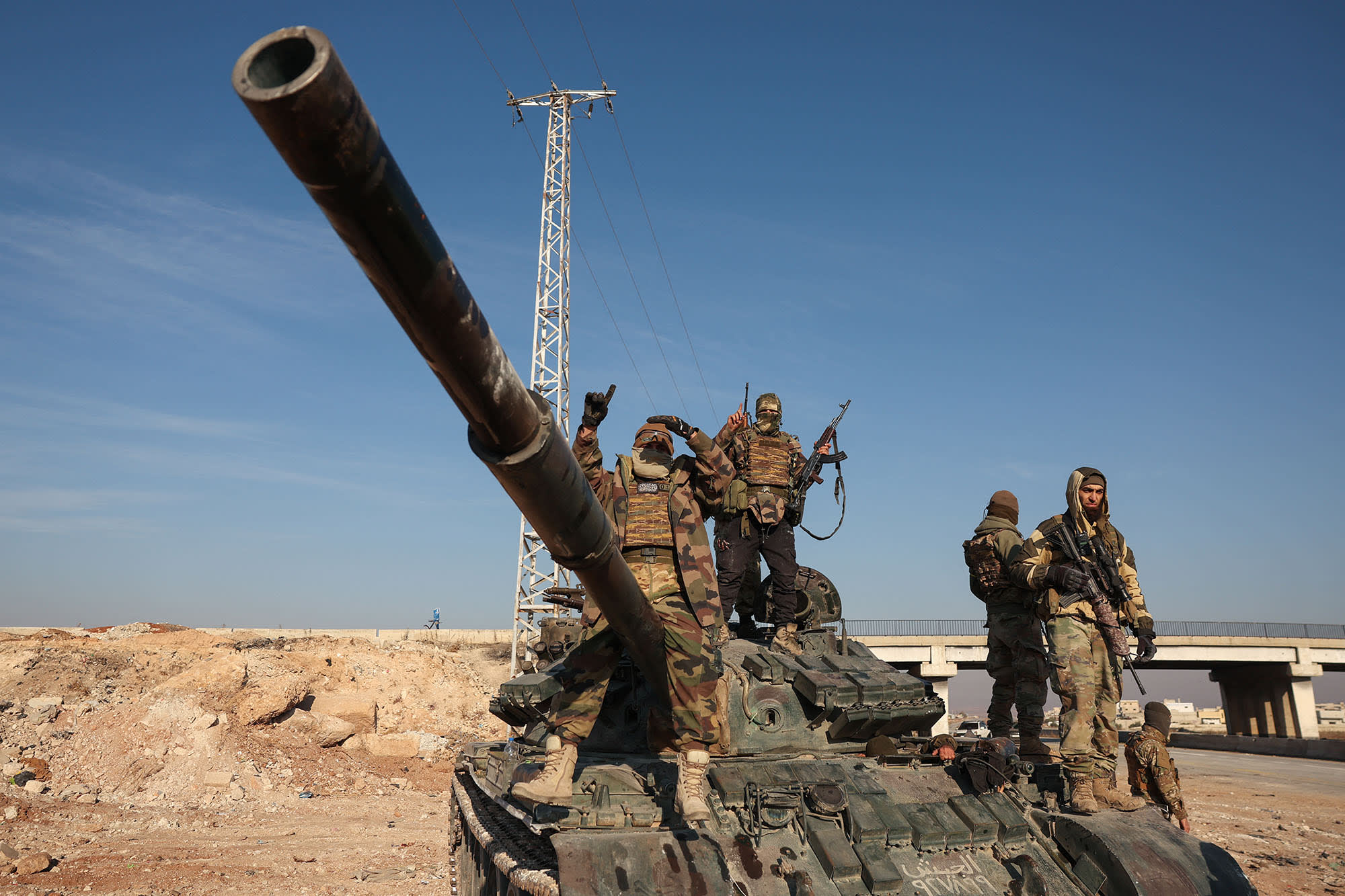 Anti-government fighters stand on abandoned Syrian army vehicles