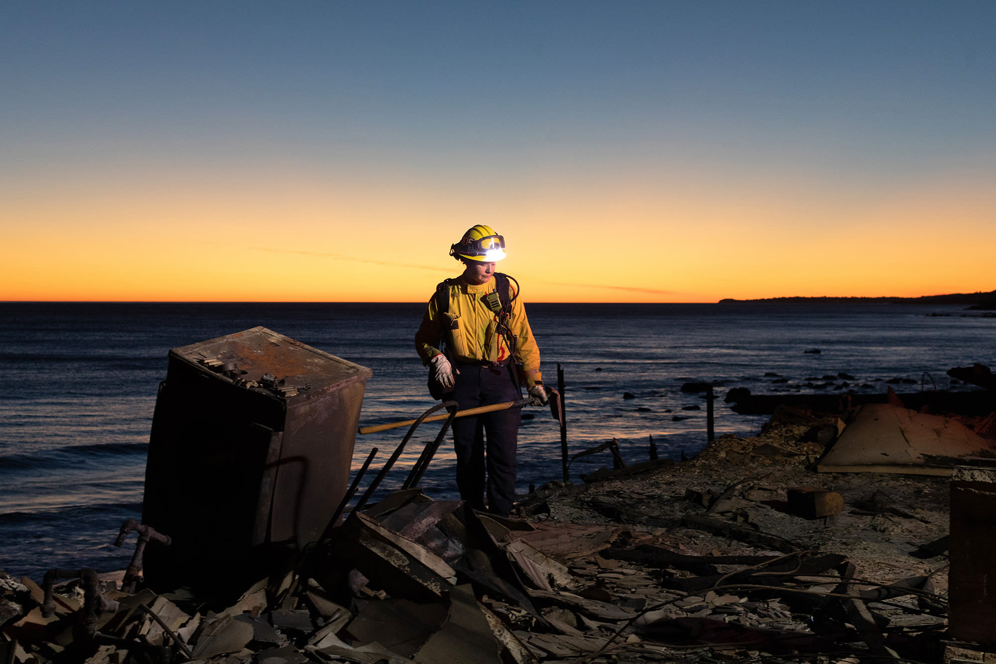 A firefighter searches for hotspots in a burned home