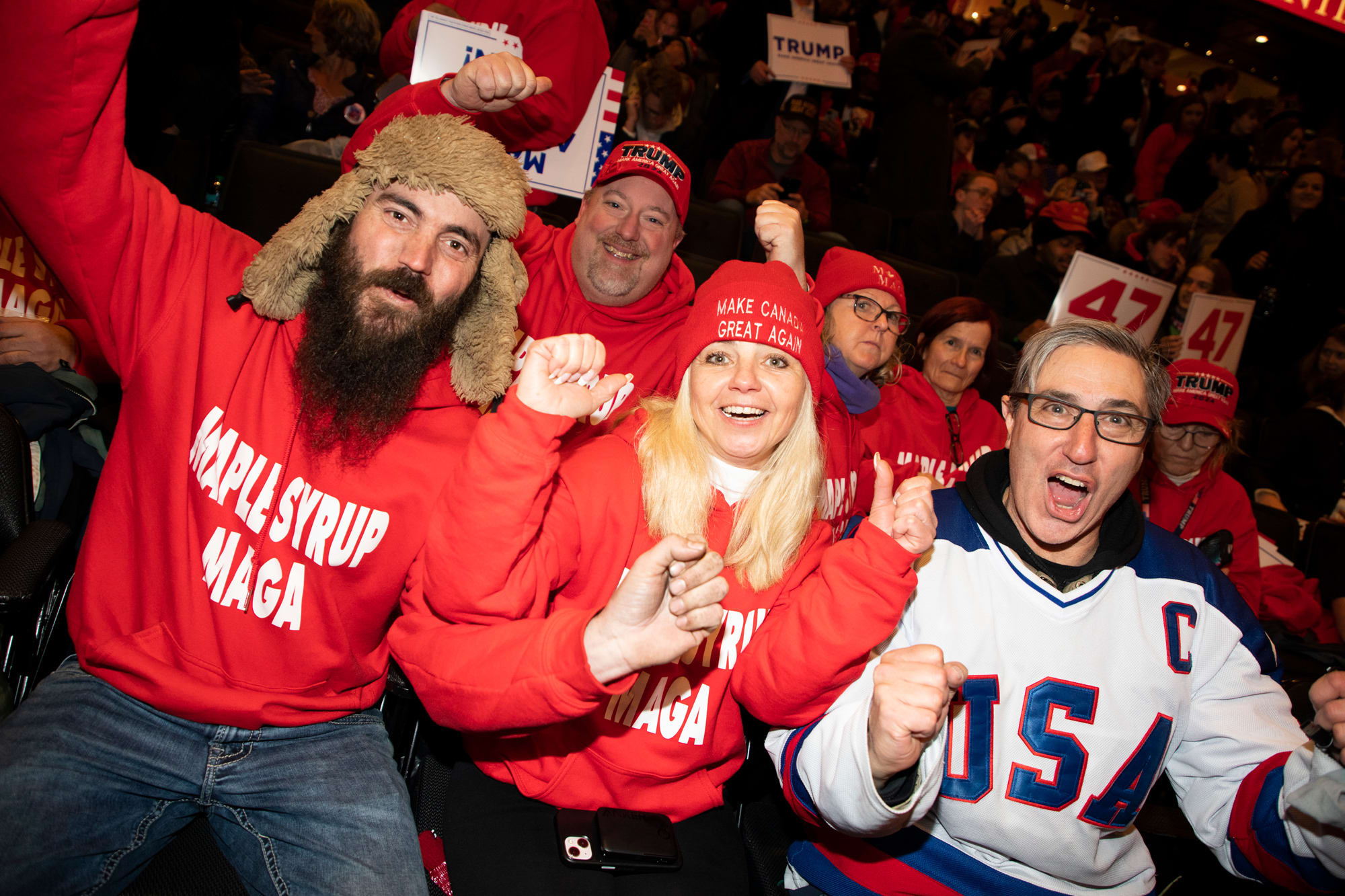 People wearing Trump merch cheer from the stadium seats