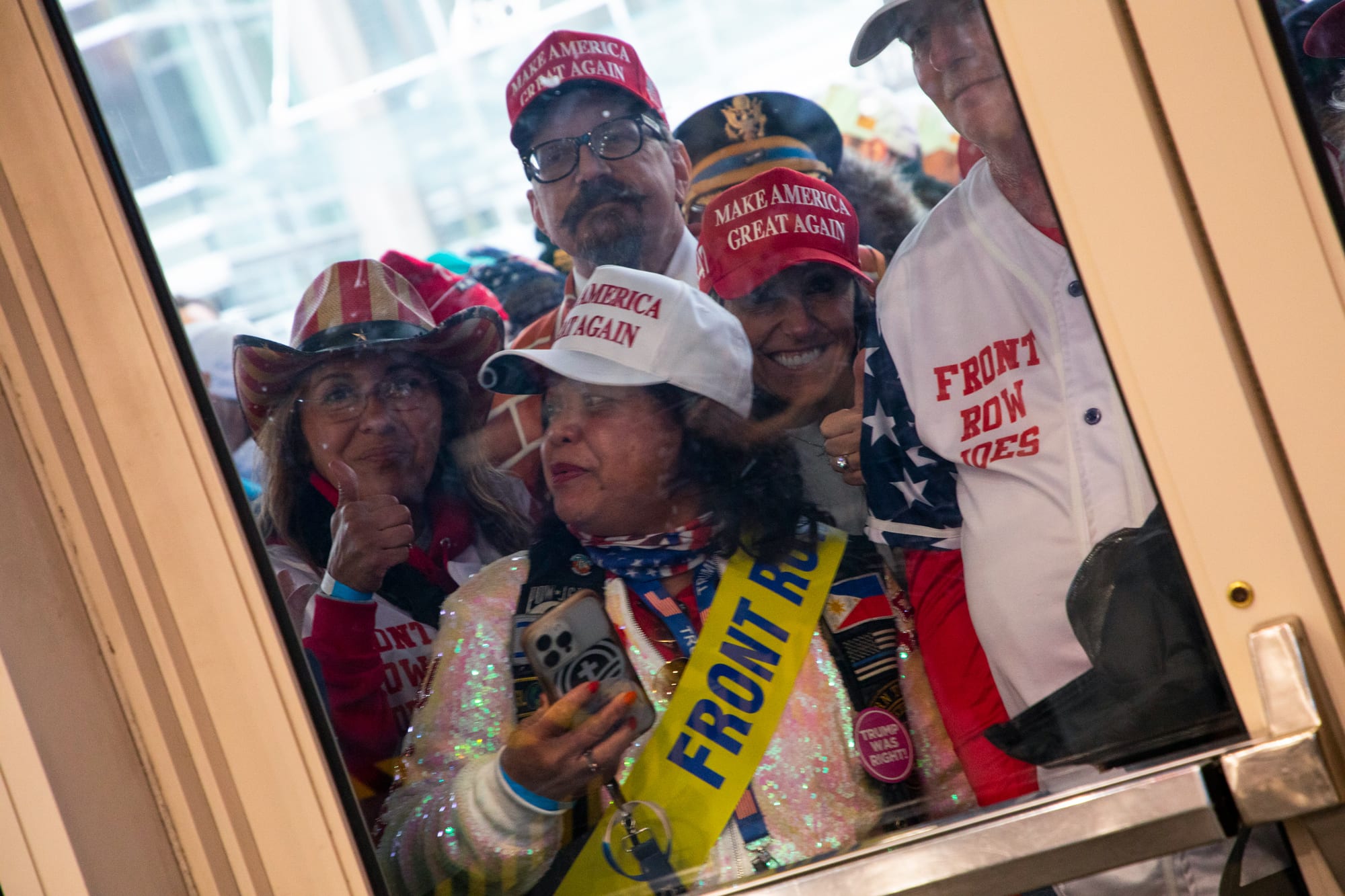 People wait outside of a door with a glass panel