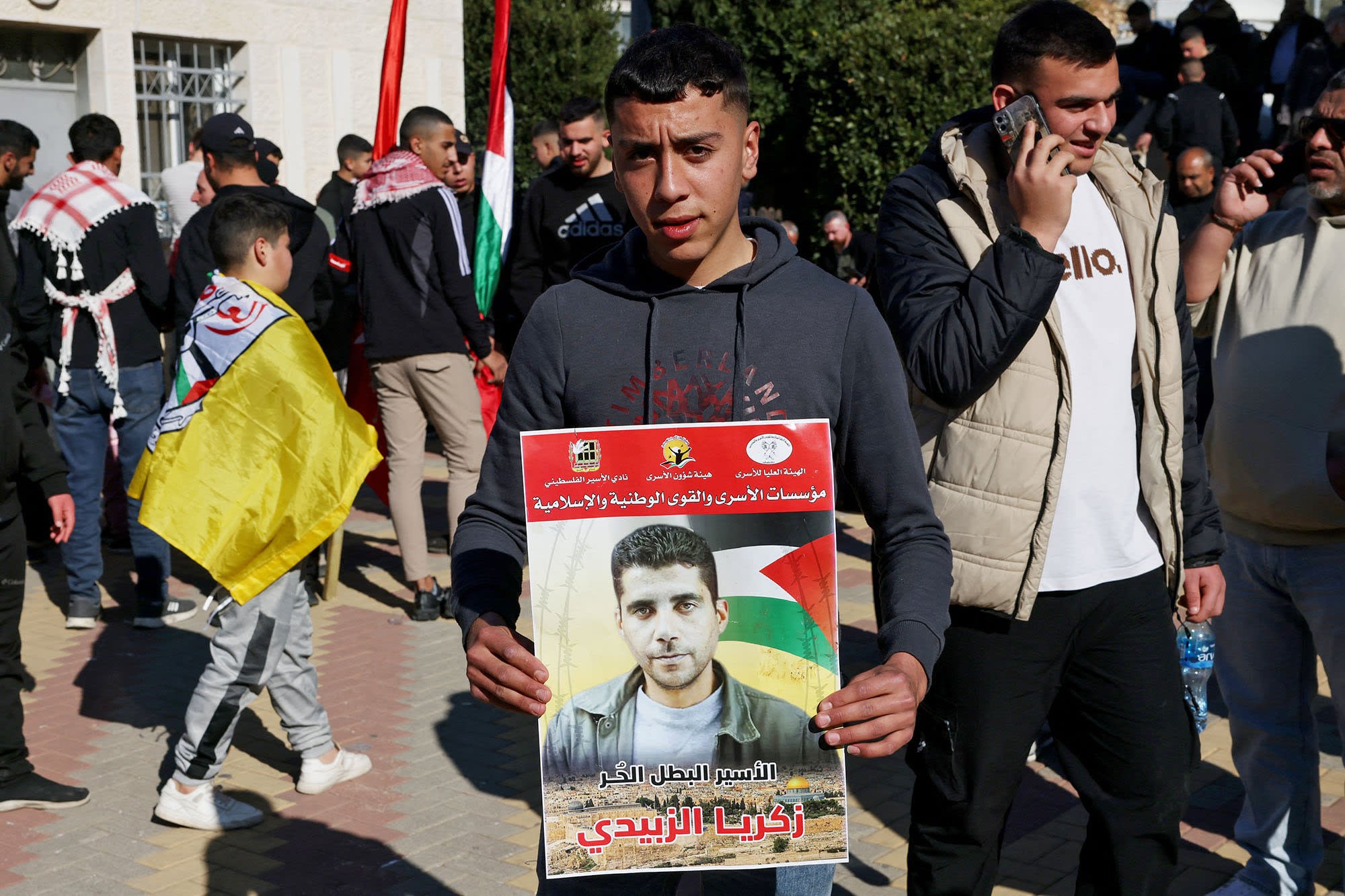 A Palestinian youth holds a portrait of Zakaria Zubeidi, a leader of Al-Aqsa Martys Brigades, as people gathered in Ramallah in the occupied West Bank to receive released Palestinian prisoners.