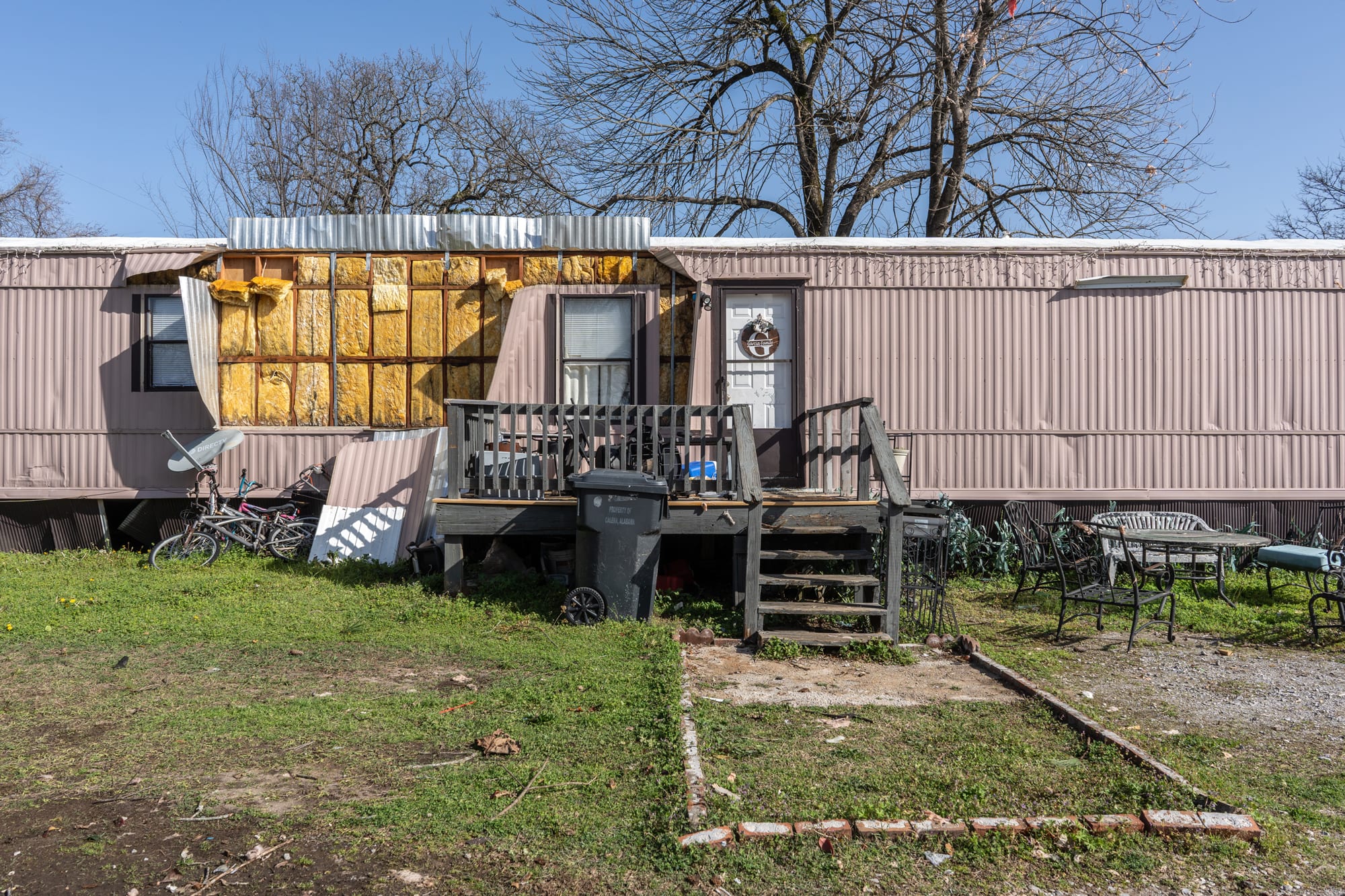 A mobile home shows damage, seen from outside