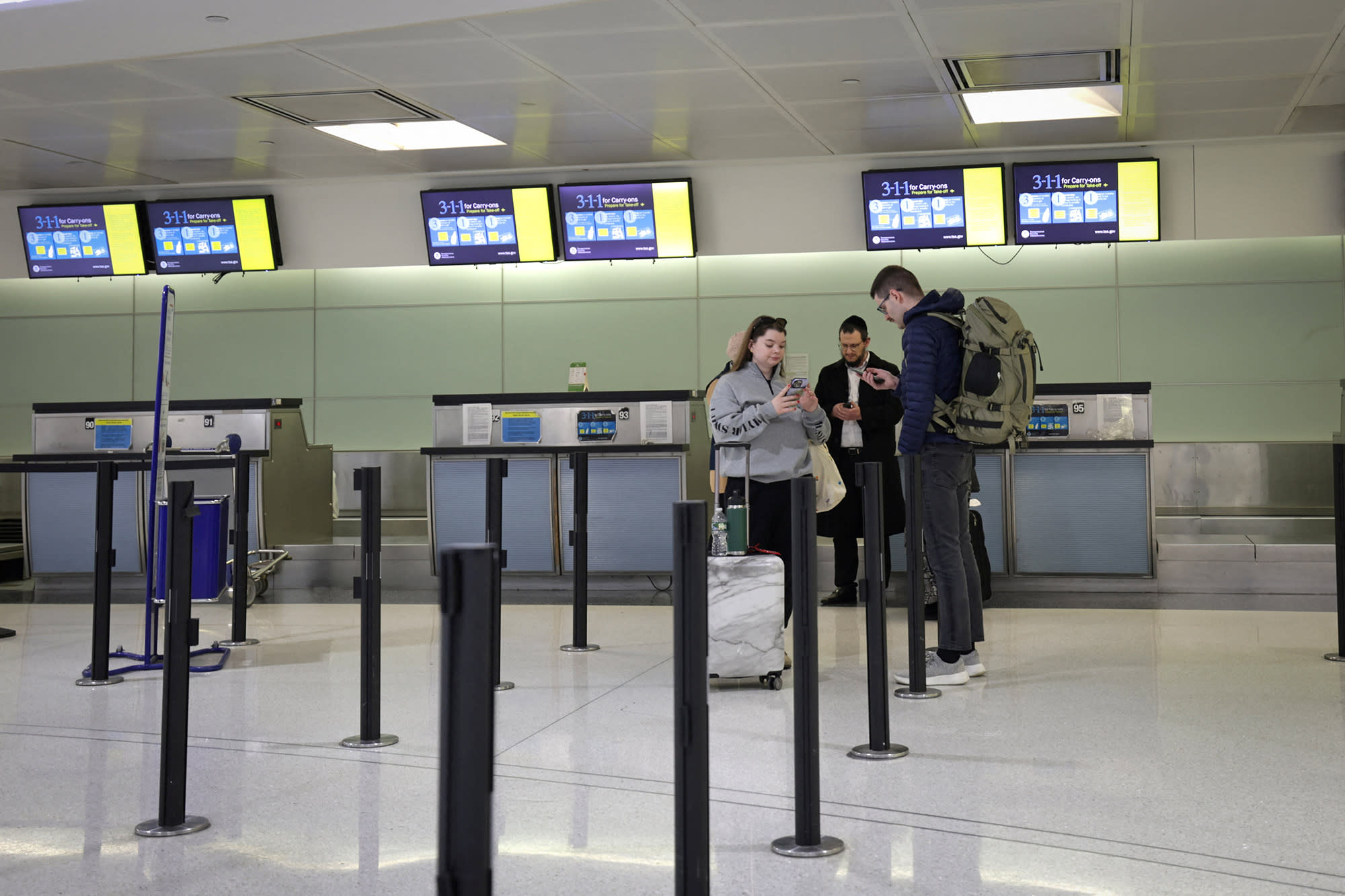 Travellers with cancelled British Airways flights stand near the airlines check-in area at Newark International Airport in New Jersey on March 21, 2025. 