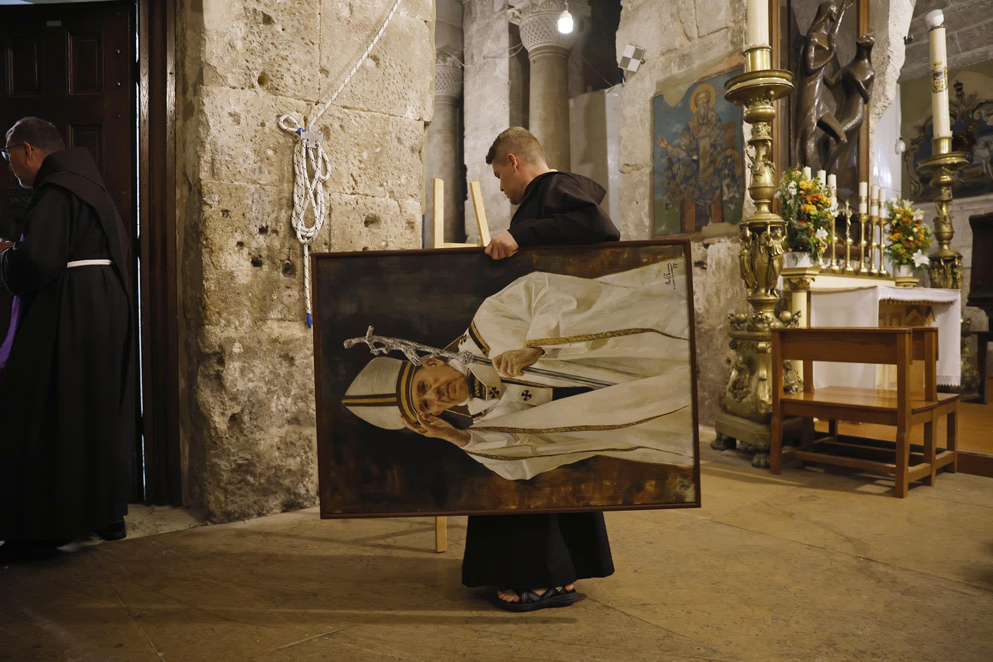Priests erect a portrait of Pope Francis at the Church Of The Holy Sepulchre on April 21, 2025 in Jerusalem.