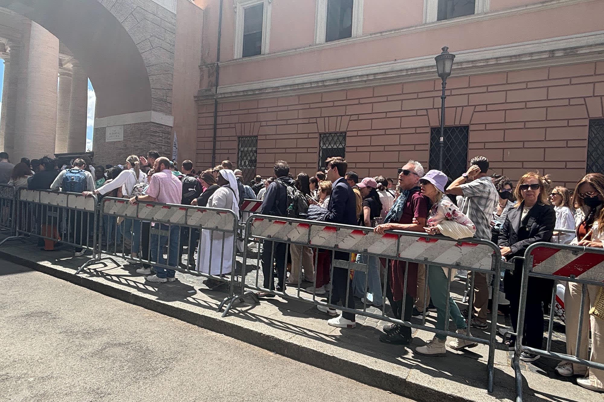 People wait at the north gates to have their bags checked before entering St. Peter's Square at the Vatican on May 8, 2025.