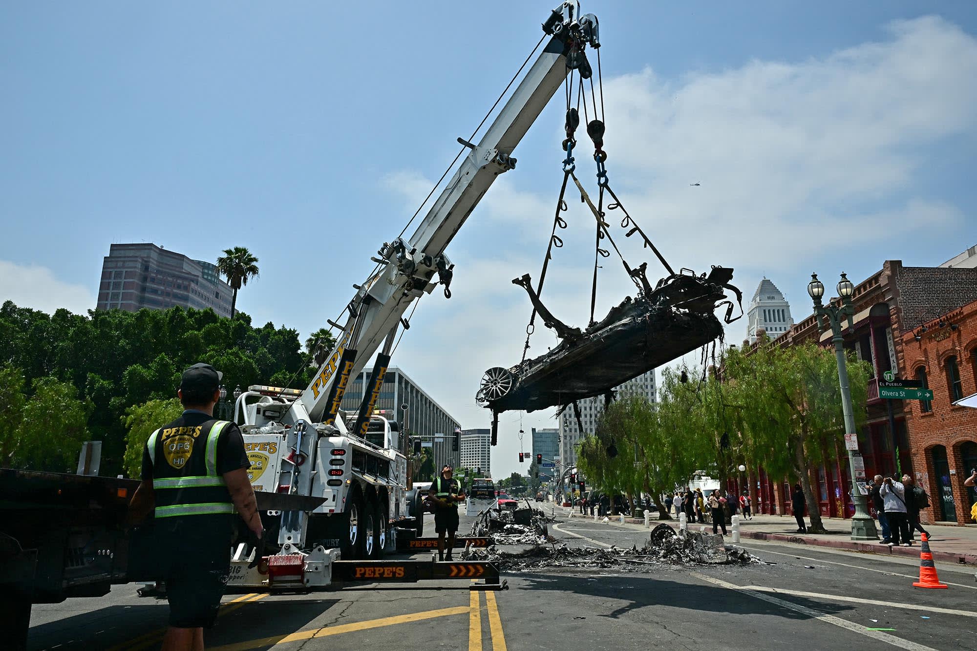 A work crew remove a charred Waymo vehicle on June 9, 2025, that was burned during a night of protests in response to federal immigration operations in Los Angeles.