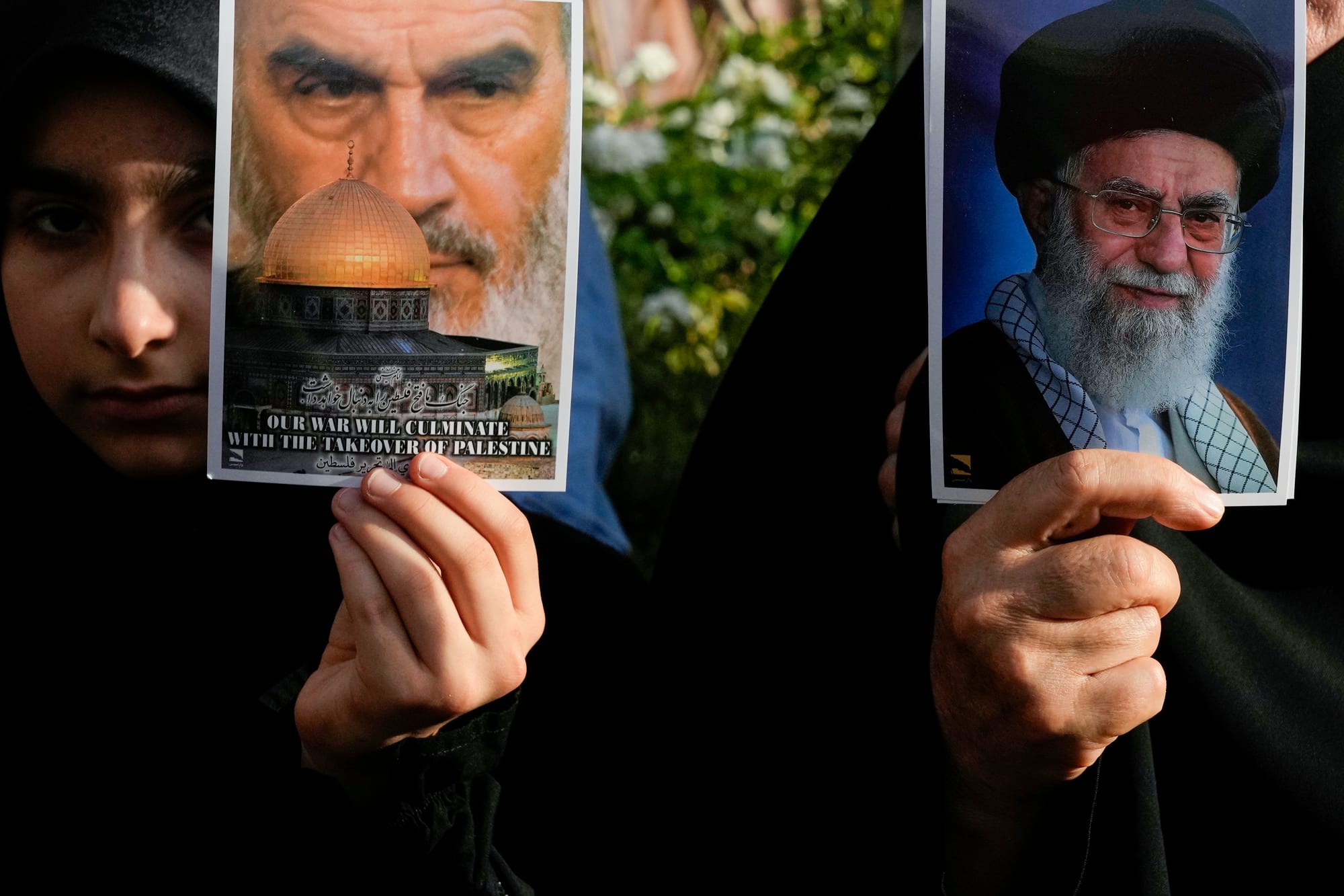 A protester holds a poster of the Supreme Leader Ayatollah Ali Khamenei, right, as the other one holds a poster showing the late revolutionary founder Ayatollah Khomeini