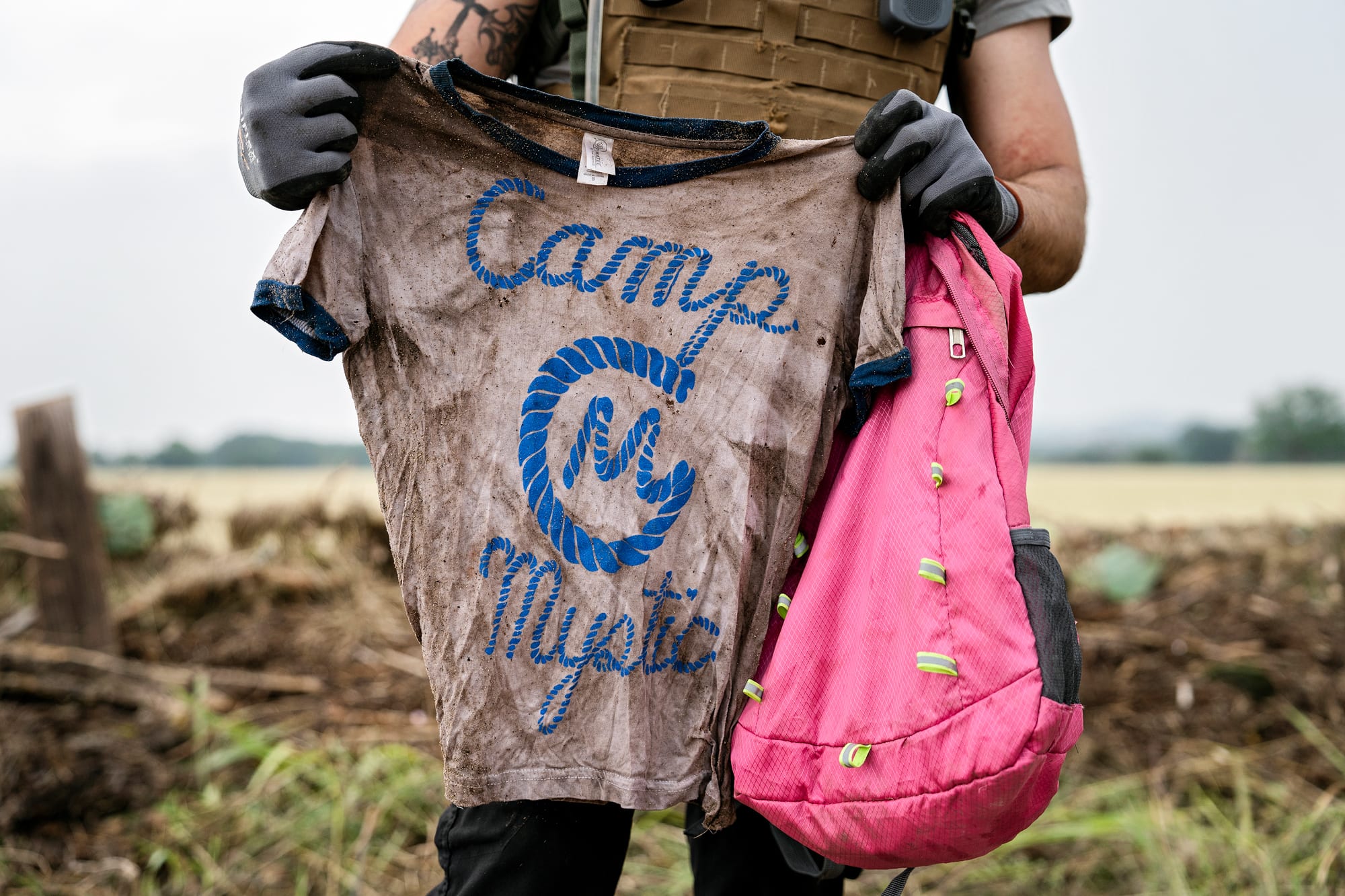 A search and rescue volunteer holds a T-shirt and backpack with the words Camp Mystic on them