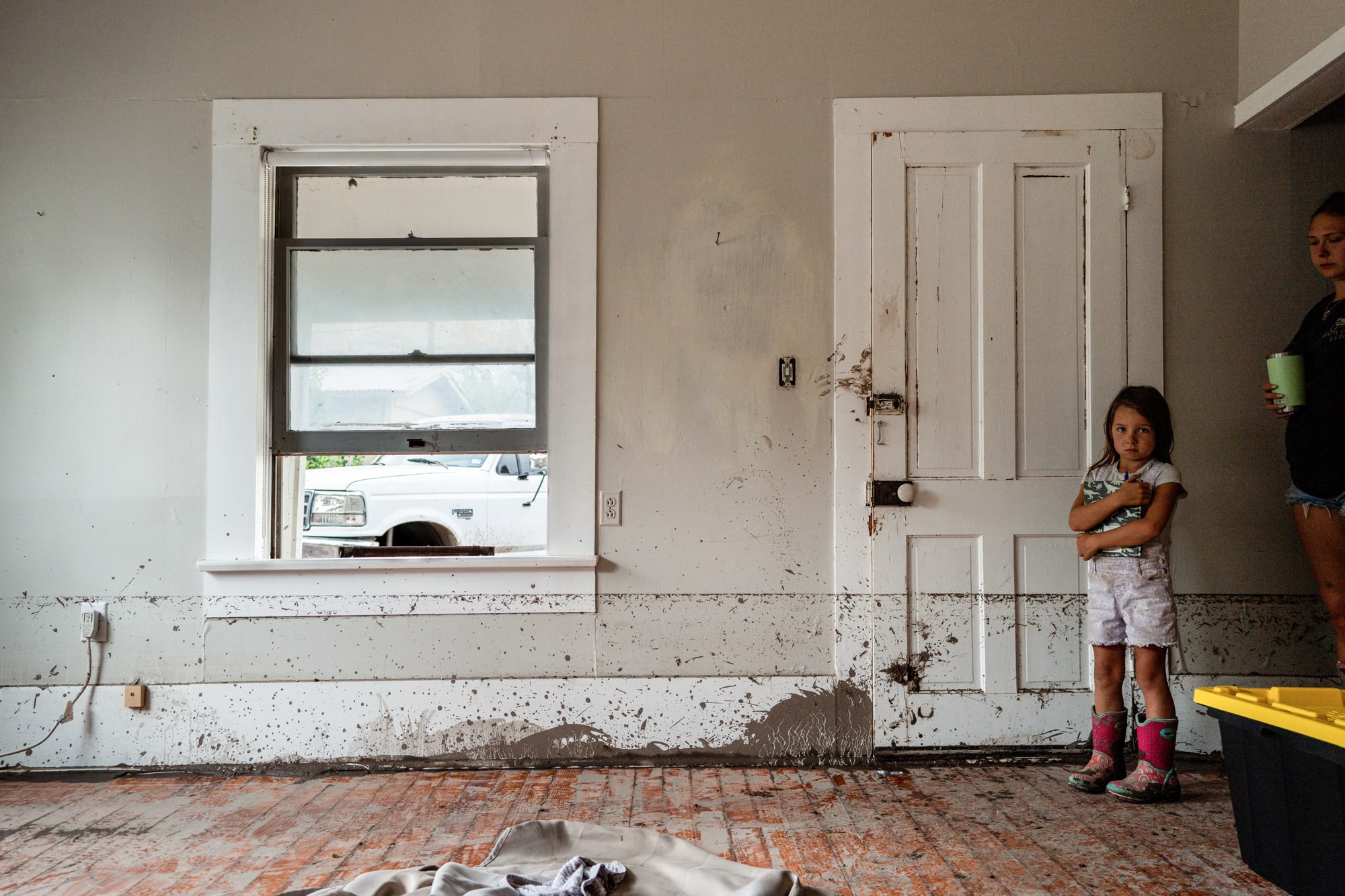 A little girl stands by the doorway of a room with flood damage