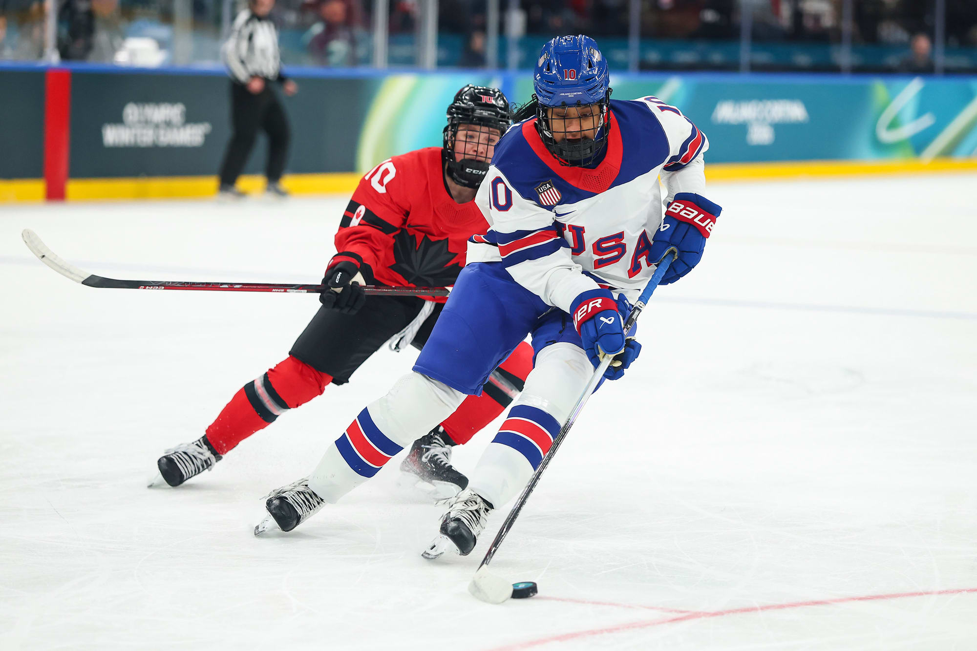 Laila Edwars controls the puck on the ice in front of an opposing team player