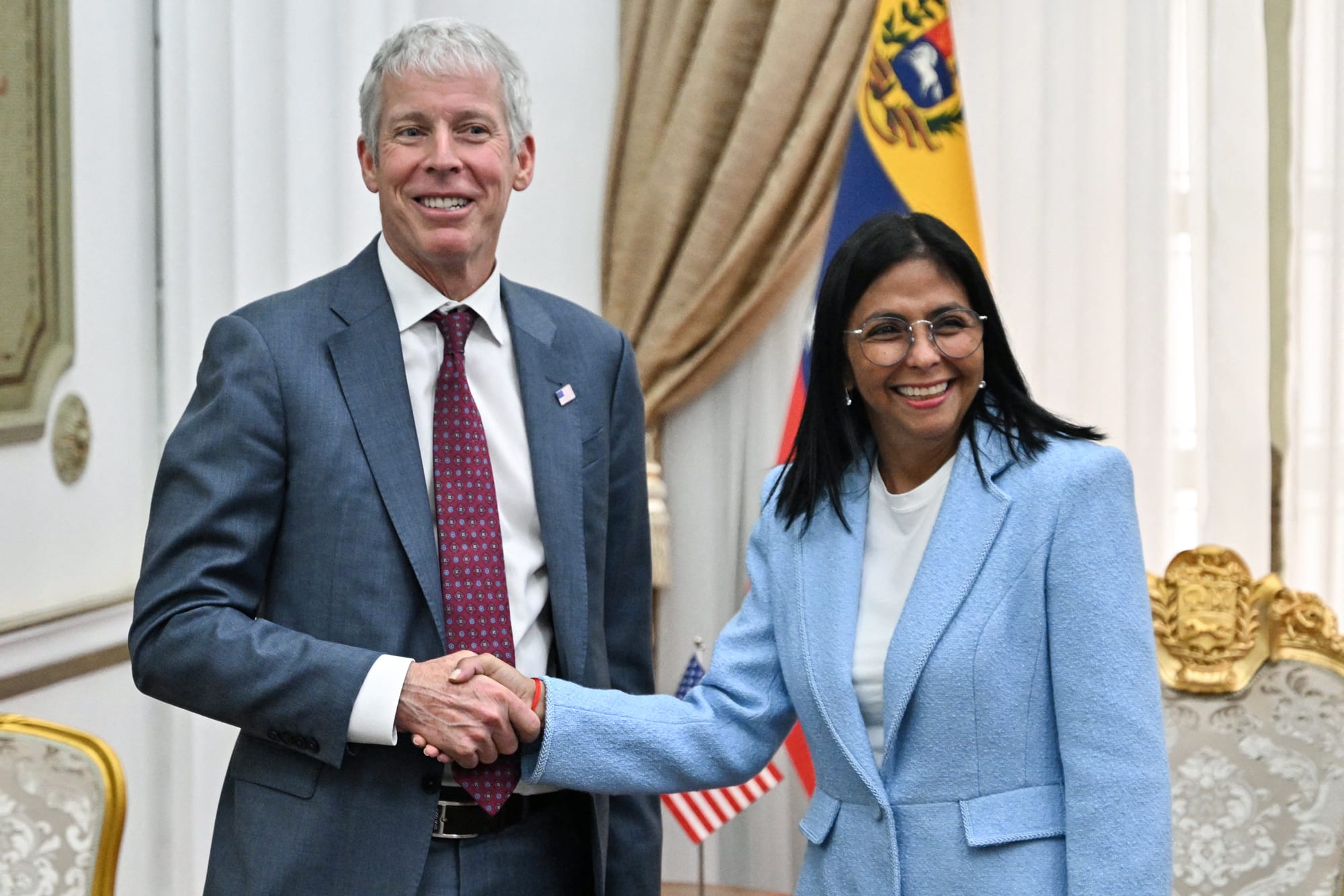 Chris Wright, left, shakes hands with Delcy Rodriguez