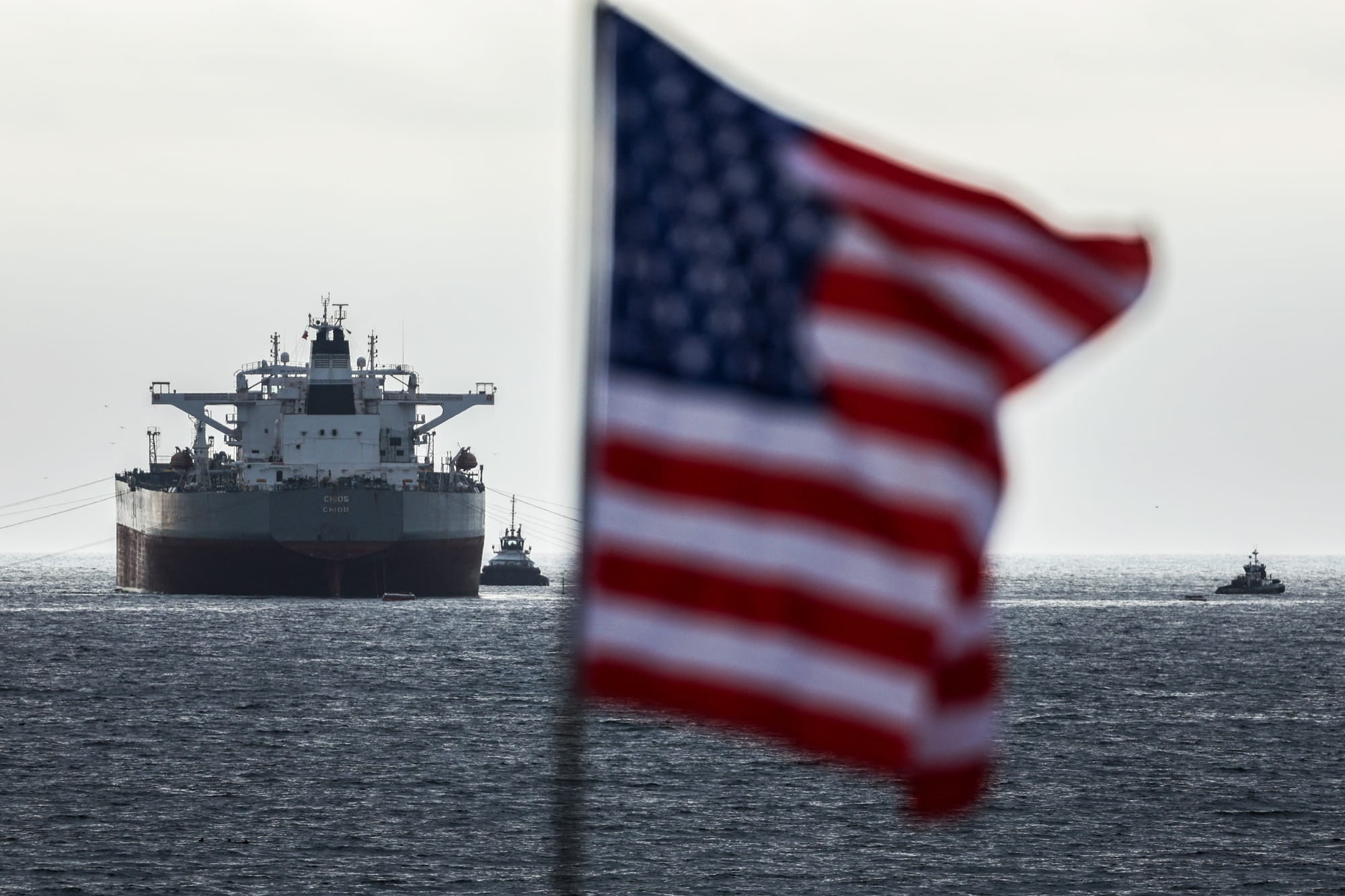 The CHIOS crude oil tanker sits on the water, a US flag waves in the foreground