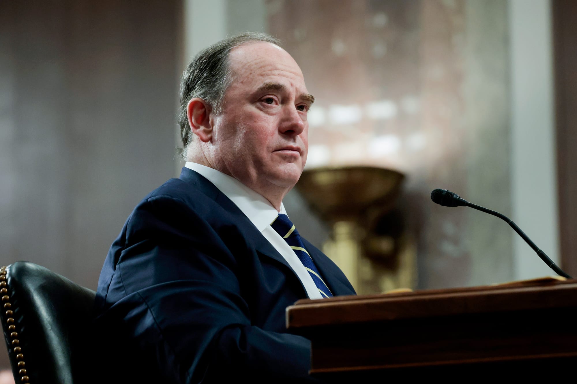 John Phelan seated in front of a desk with a microphone