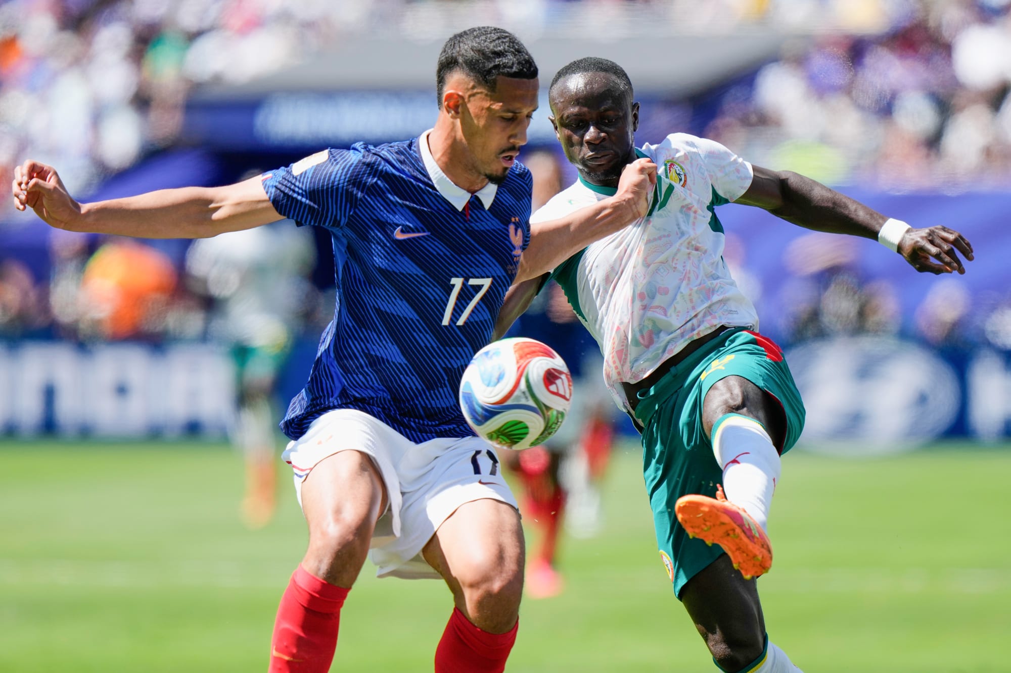 William Saliba, left, and Sadio Mane battle for the soccer ball on the field
