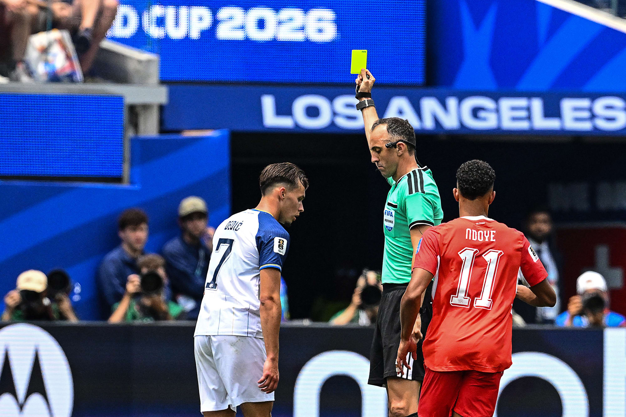 Portuguese referee Joao Pinheiro shows a yellow card to Bosnia-Herzegovina's defender Amar Dedic