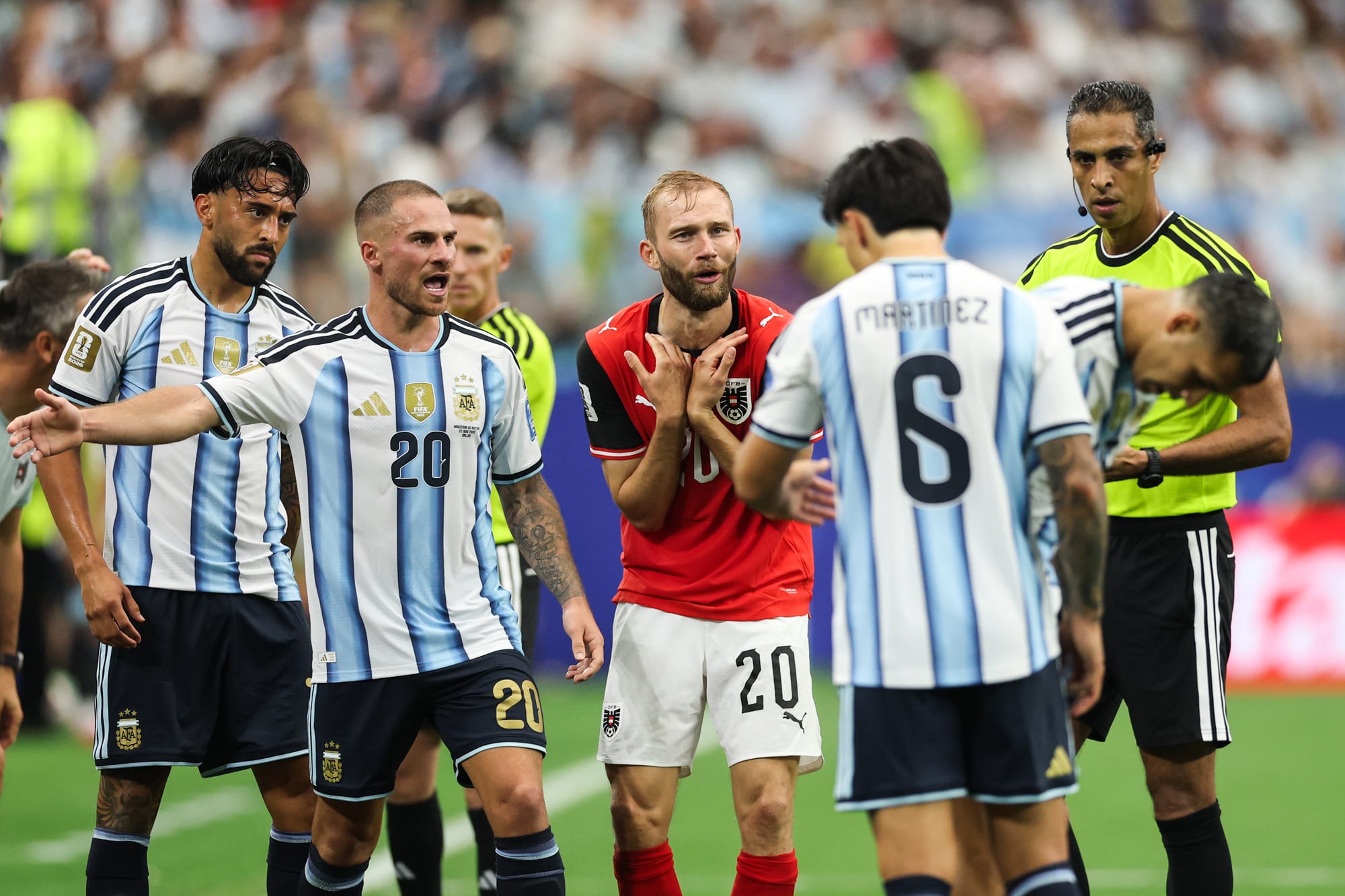 Konrad Laimer, center, is angered and yells on the soccer field while standing between Argentina players