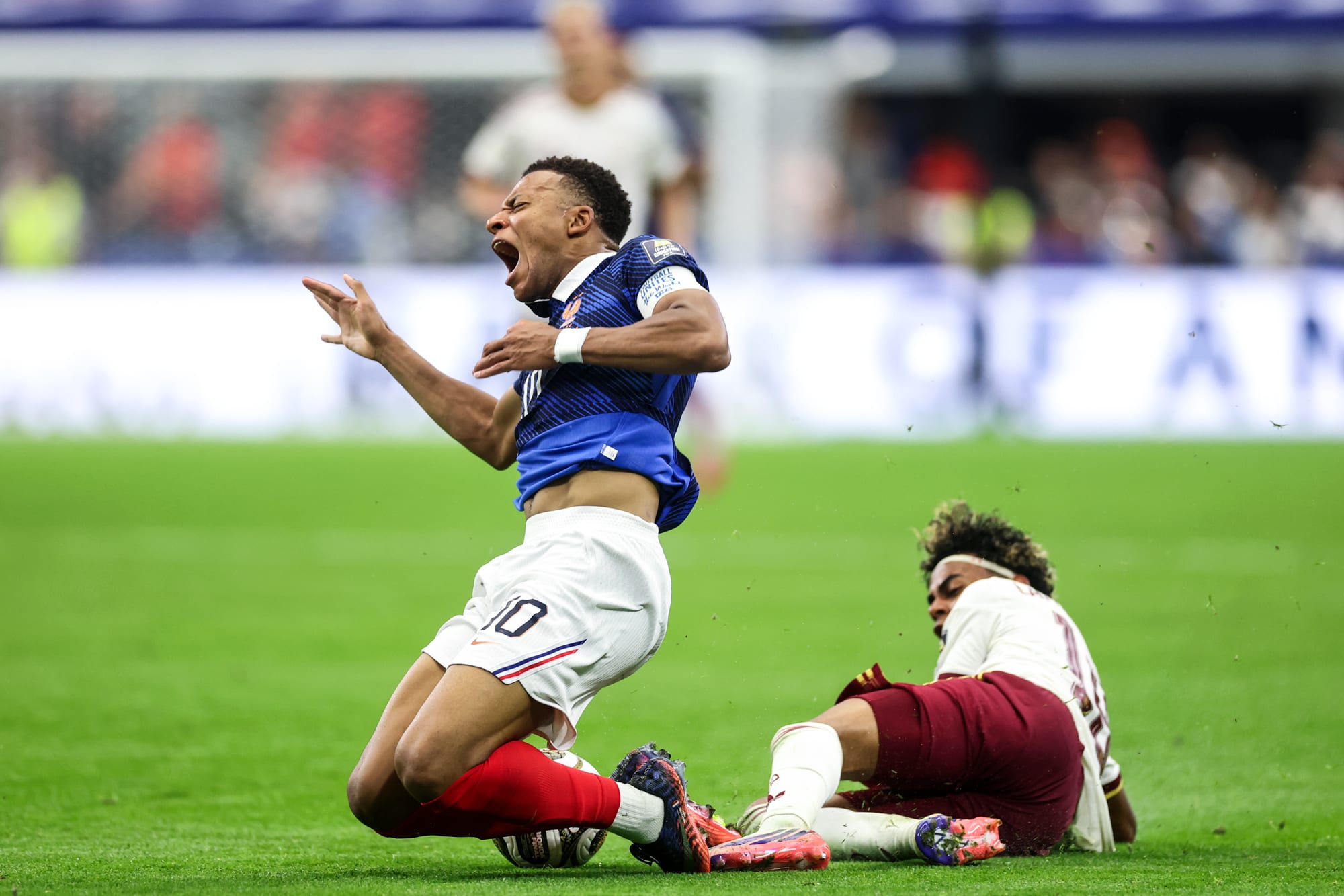 Kylian Mbappe falls next to Lamine Yamal, right, who is already on the ground on the soccer field