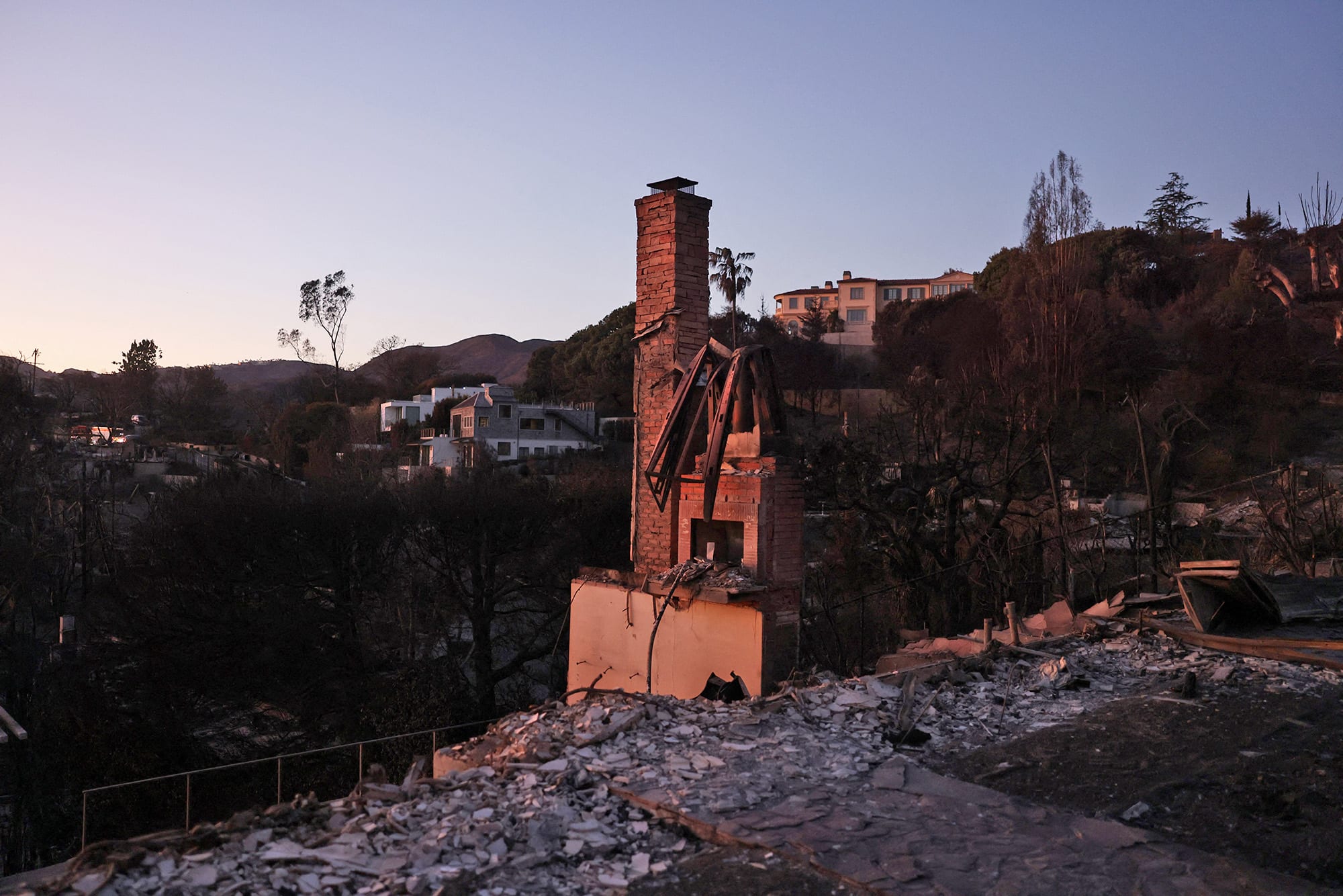 A fireplace and chimney stand amid the rubble of a destroyed home 