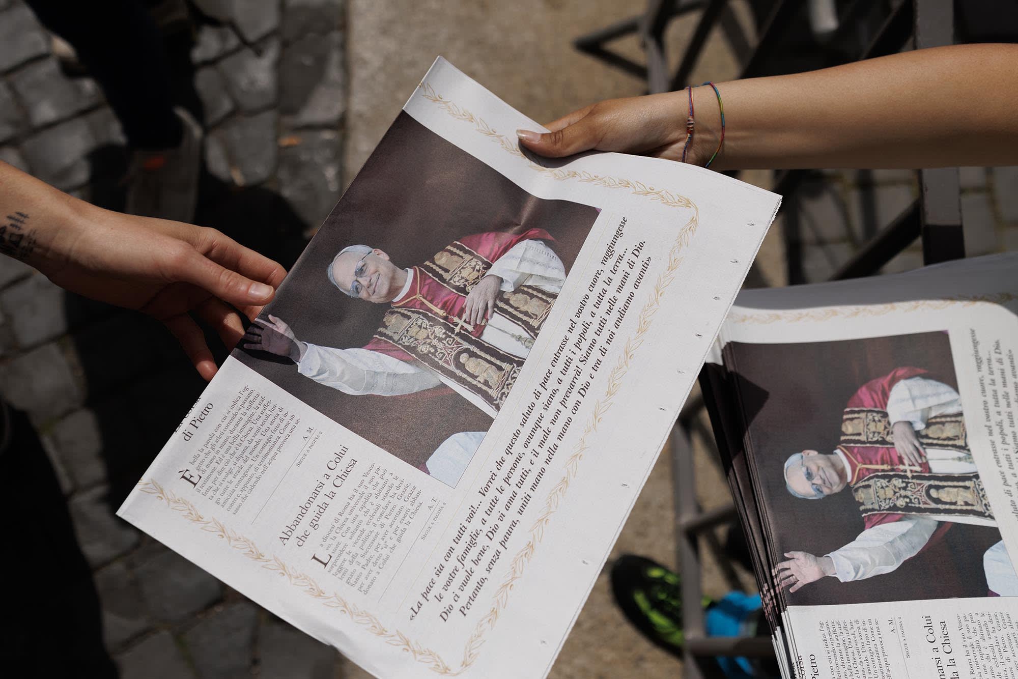 People rush to grab some of the first copies of the Vatican Newspaper 'L'Osservatore Romano' on May 9, 2025 in Vatican City.