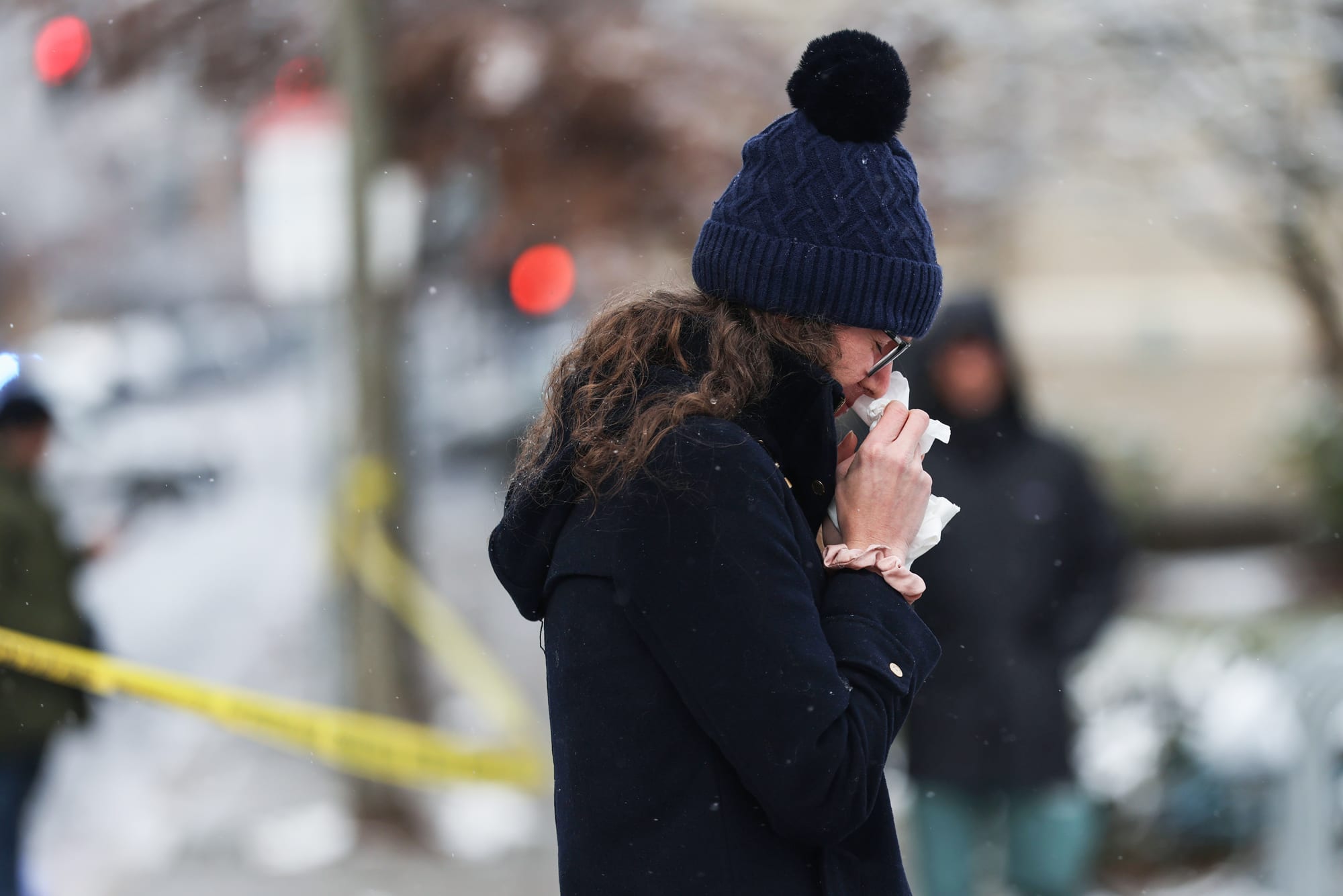 A woman cries outside, placing tissue on her face