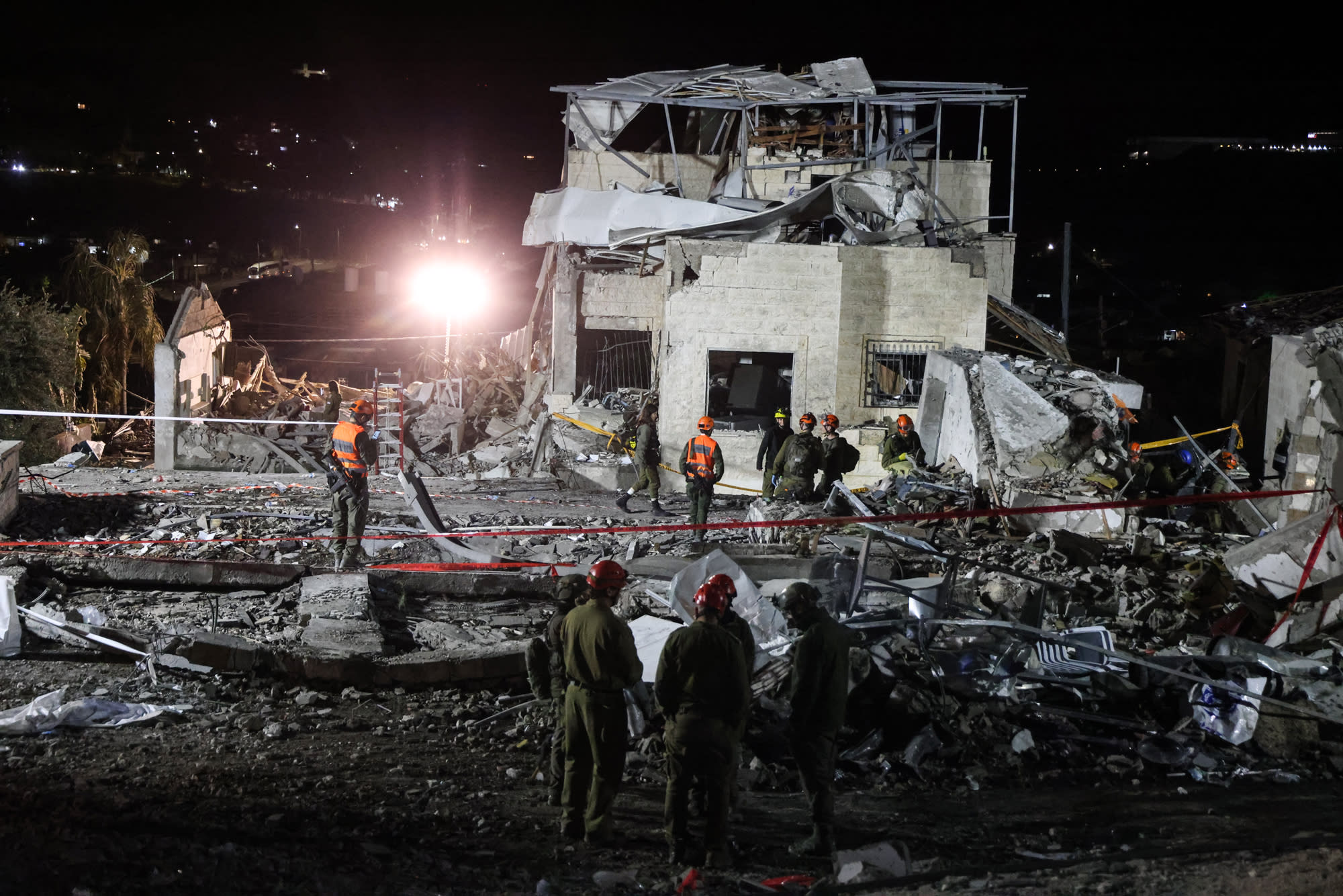 Search and rescue teams stand around a damaged building and debris
