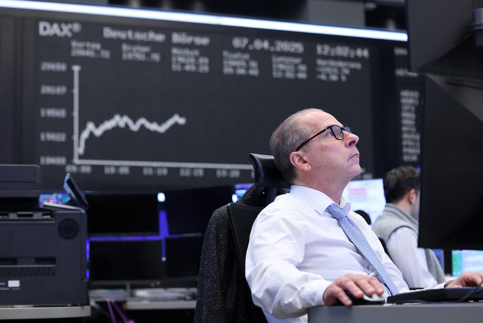 A trader works in front of a board displaying the chart of Germany's share index DAX at the stock exchange in Frankfurt am Main, western Germany, on April 7, 2025. 