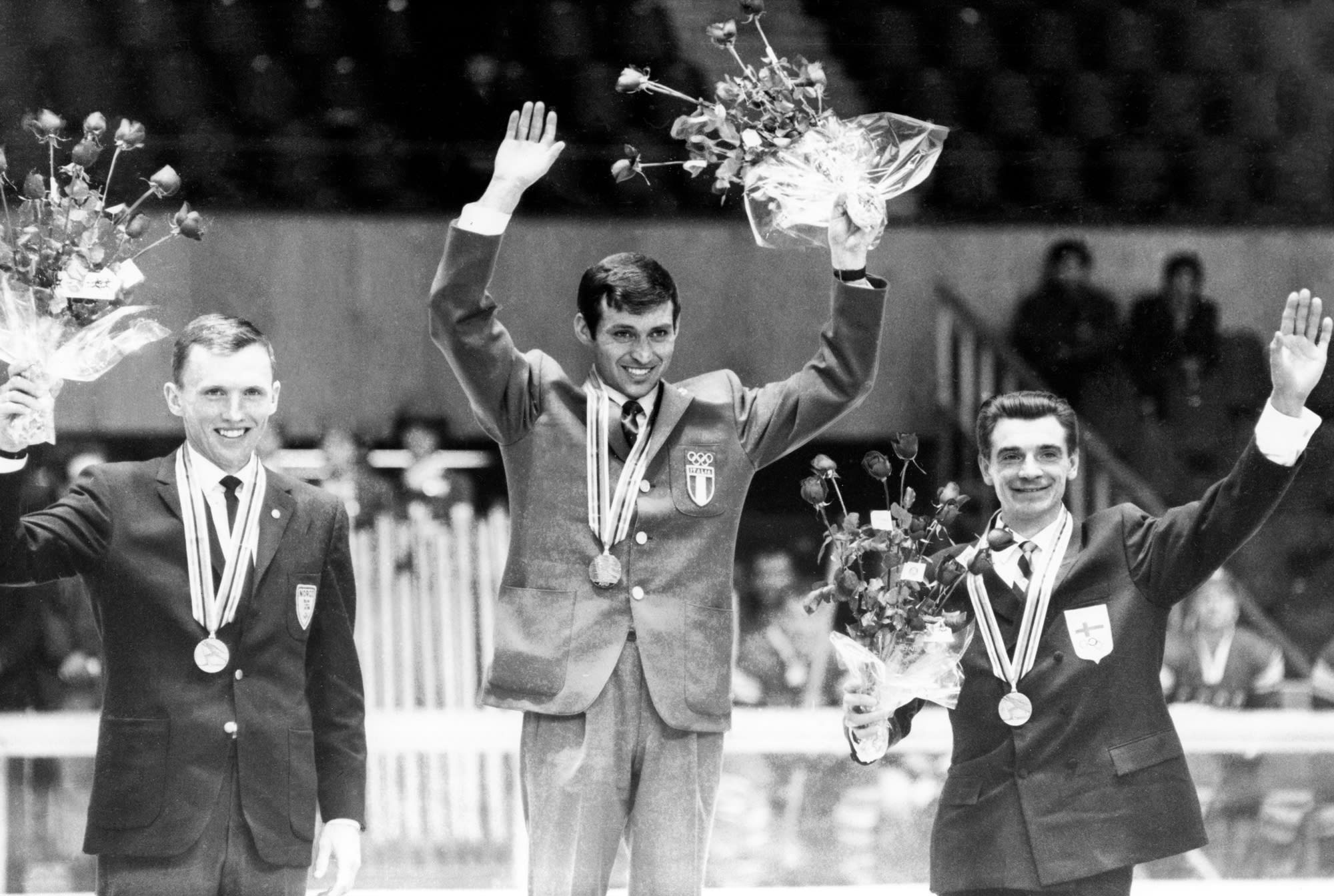 Odd Martinsen, Franco Nones, and Eero Mäntyranta hold bouquets of flowers and wear medals on stage