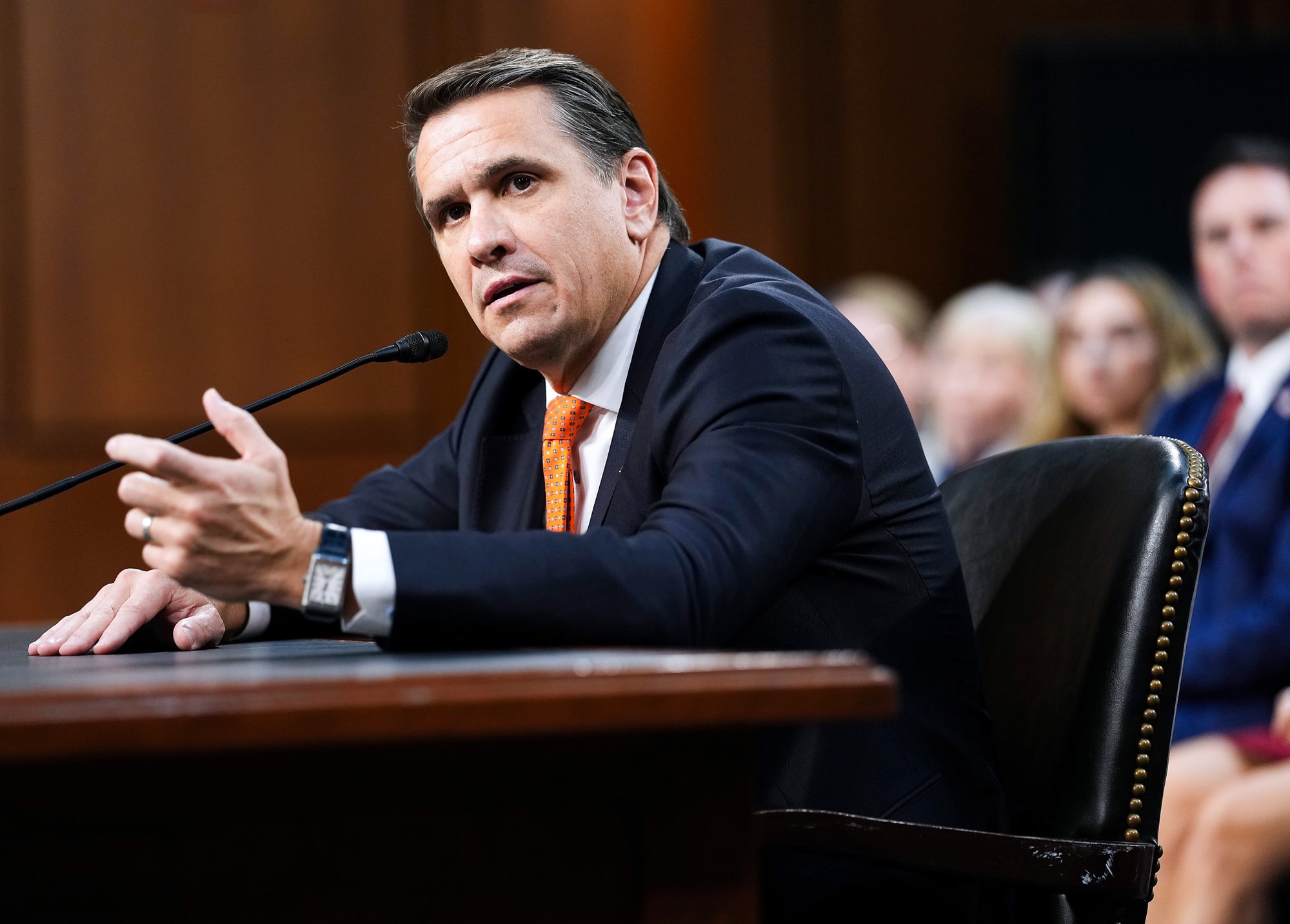 Todd Blanche speaks while seated in a hearing room, a microphone is in front of him